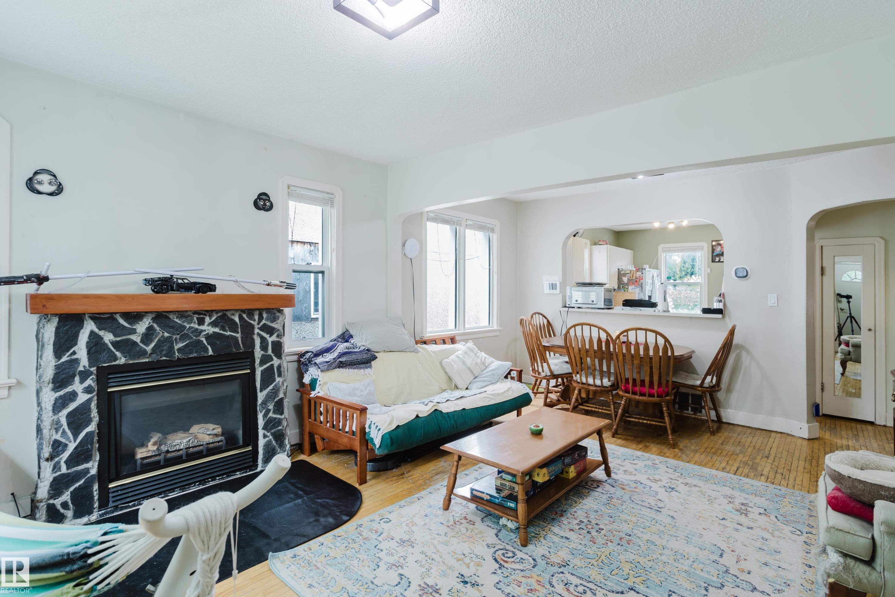 Living area featuring a stone-faced fireplace with a wood mantel - 11158 65 Street, Edmonton, AB
