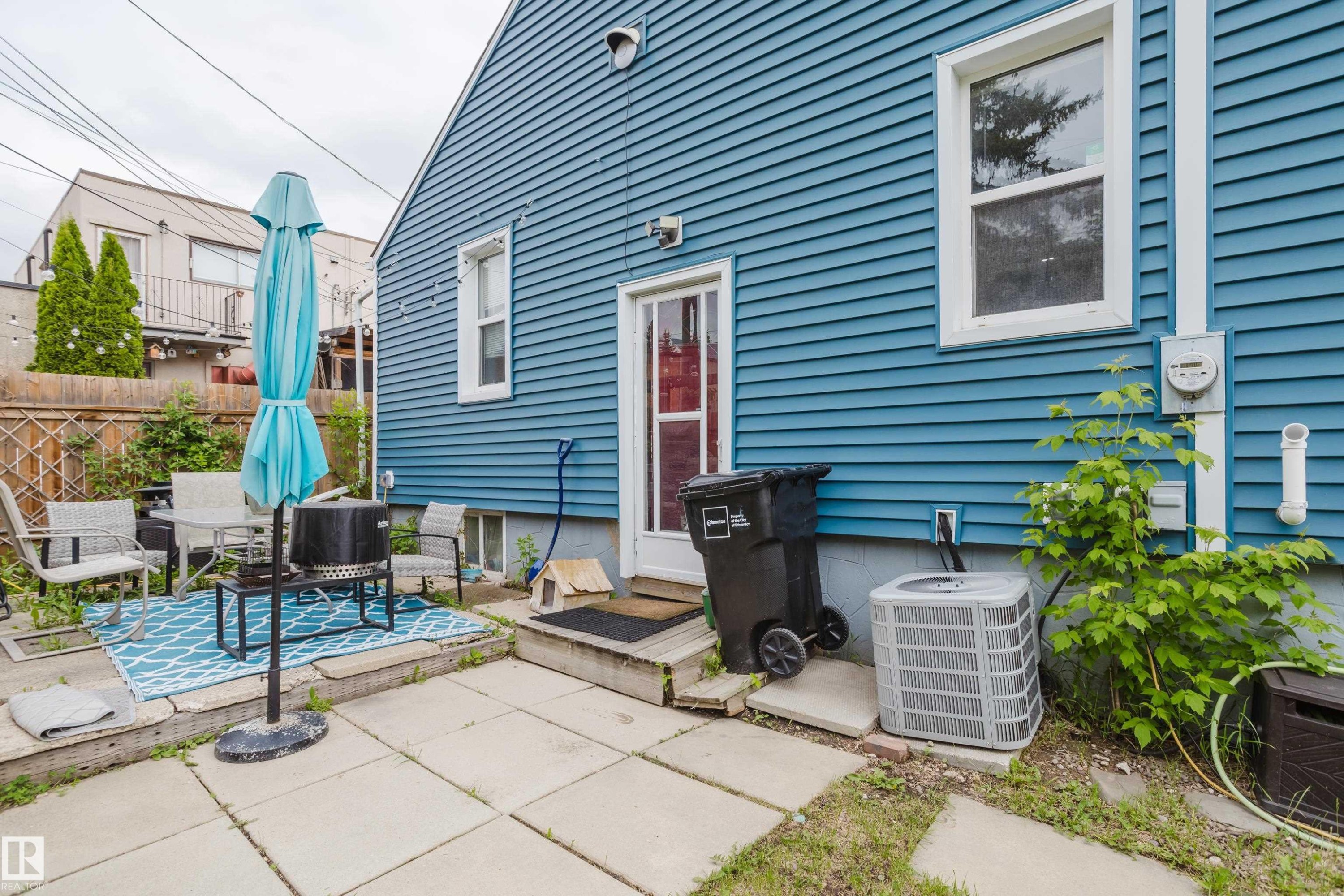 Rear exterior featuring blue horizontal siding, white trim, and a white-framed window - 11158 65 Street, Edmonton, AB