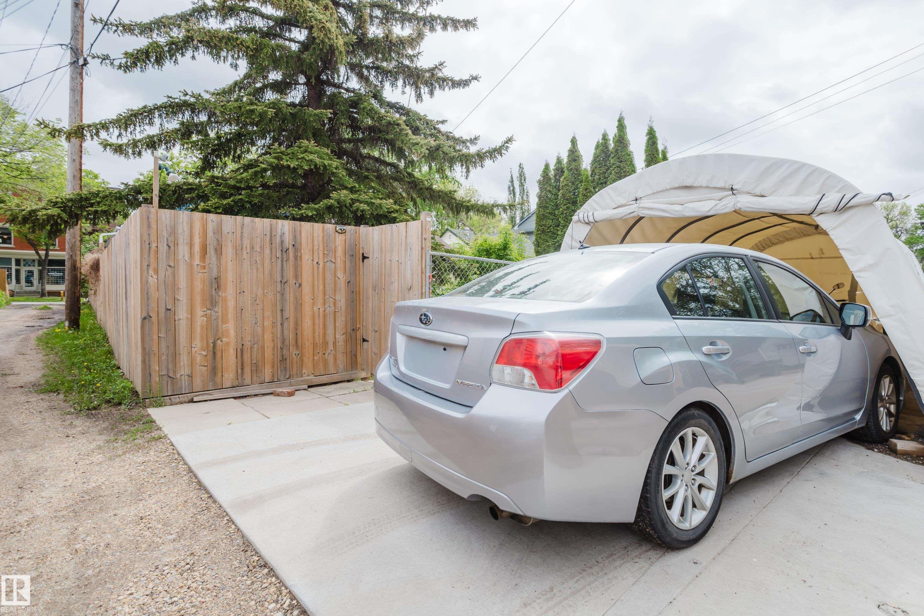 Paved concrete driveway with a wood privacy fence and mature trees - 11158 65 Street, Edmonton, AB
