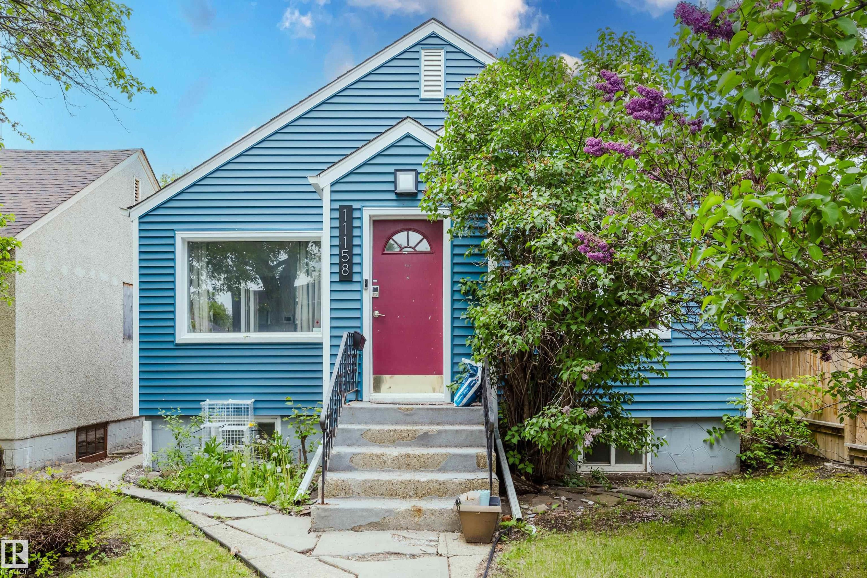 Blue siding exterior featuring a contrasting red entry door with an arched window - 11158 65 Street, Edmonton, AB
