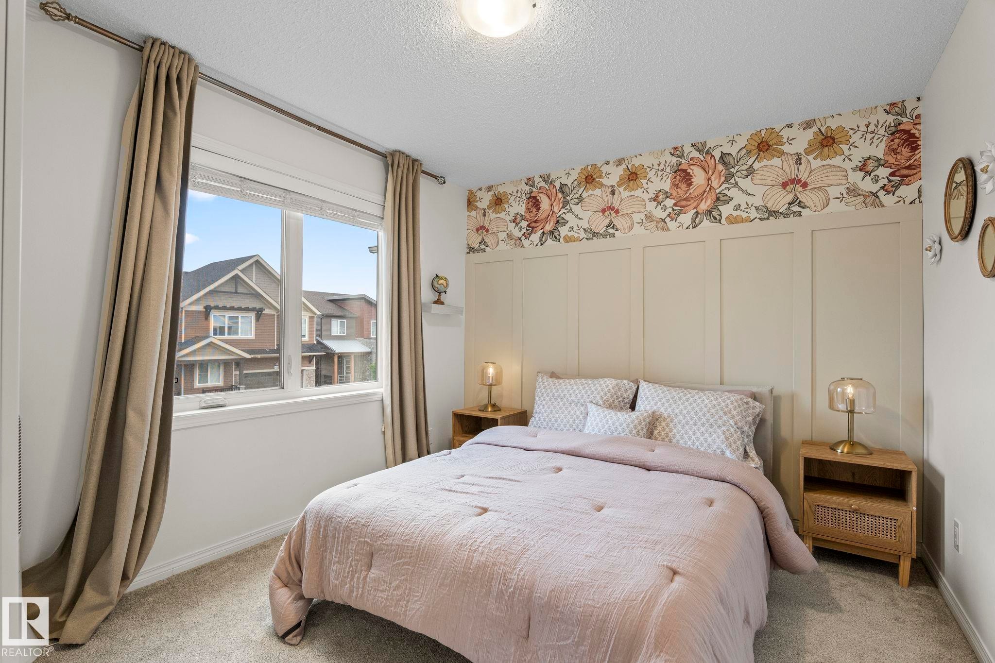 Bedroom featuring a decorative accent wall with floral wallpaper and board and batten detailing - 20227 17Ave, Edmonton, AB