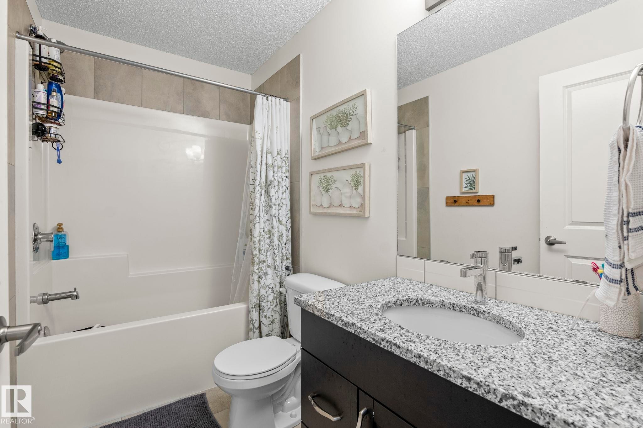 Bathroom featuring a white tub and shower combination with light-toned wall tiling - 20227 17Ave, Edmonton, AB
