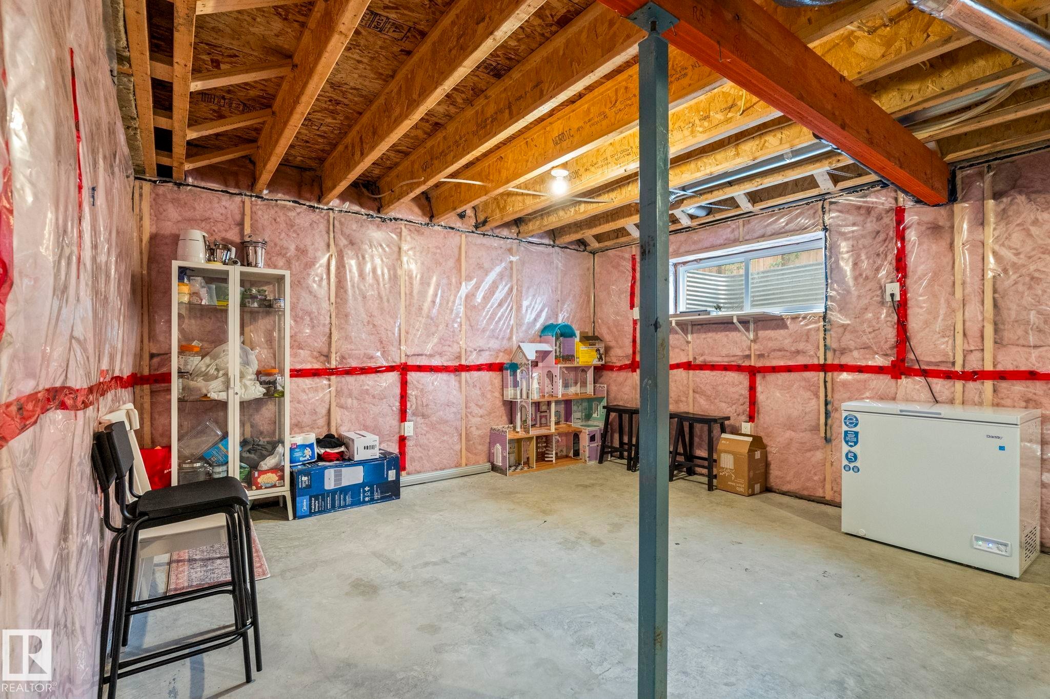 Unfinished basement offering exposed wood framing, concrete flooring, and an egress window - 20227 17Ave, Edmonton, AB