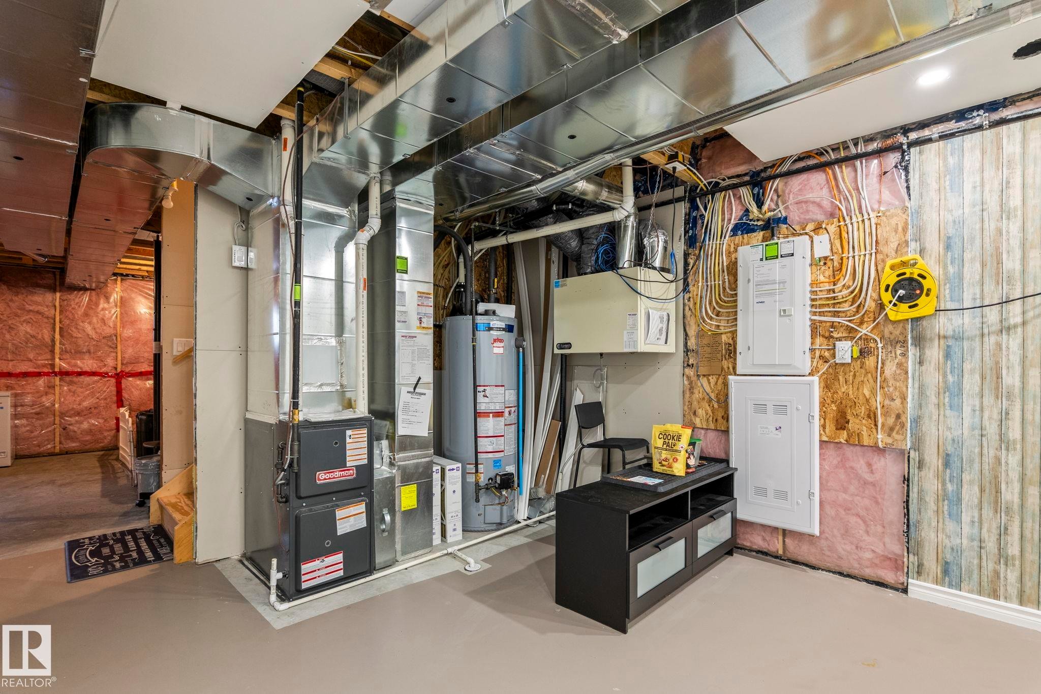 Utility area featuring a furnace, water heater, exposed ductwork, and electrical panels - 20227 17Ave, Edmonton, AB