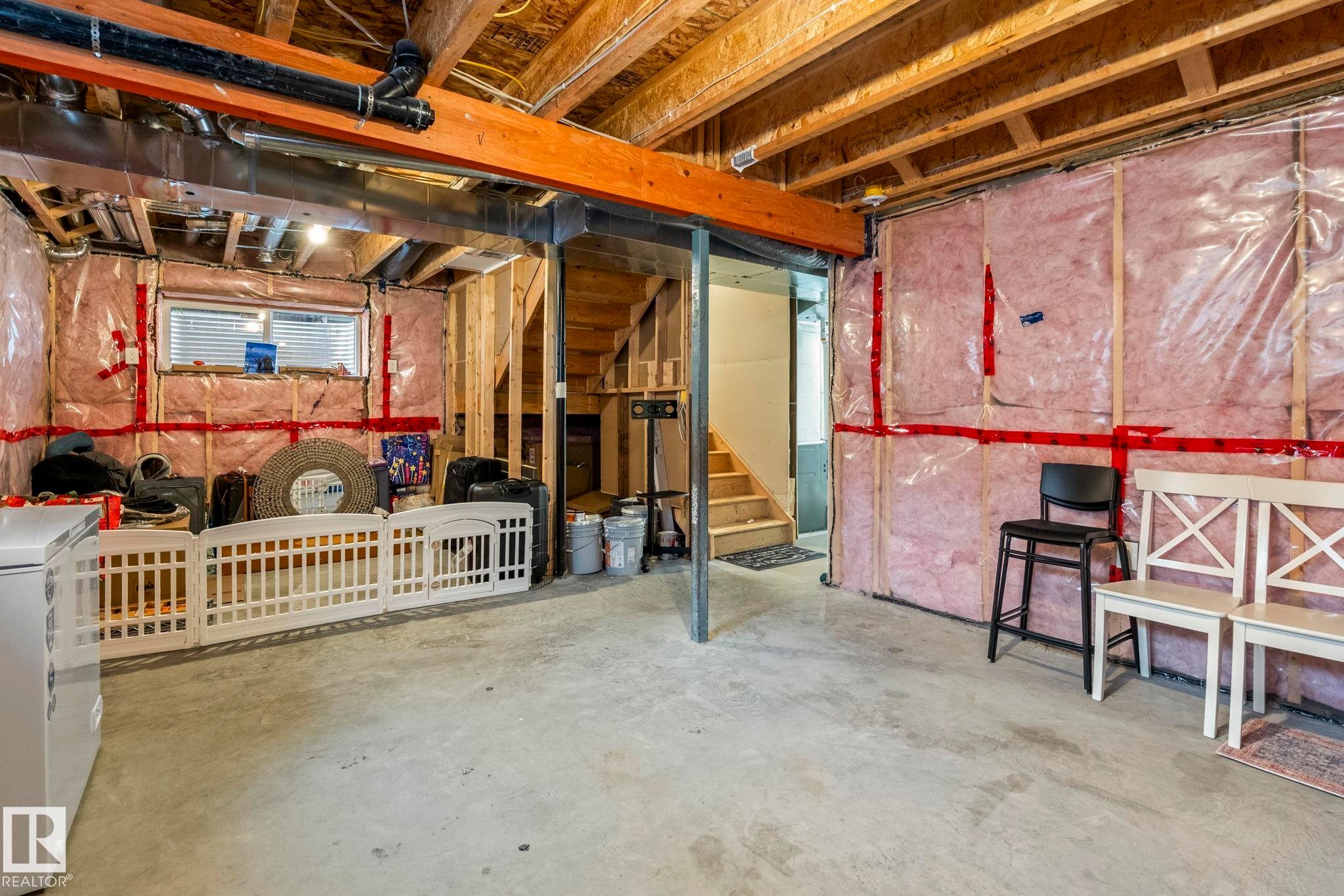 Unfinished basement space featuring exposed wooden joists, concrete flooring, and insulated walls - 20227 17Ave, Edmonton, AB