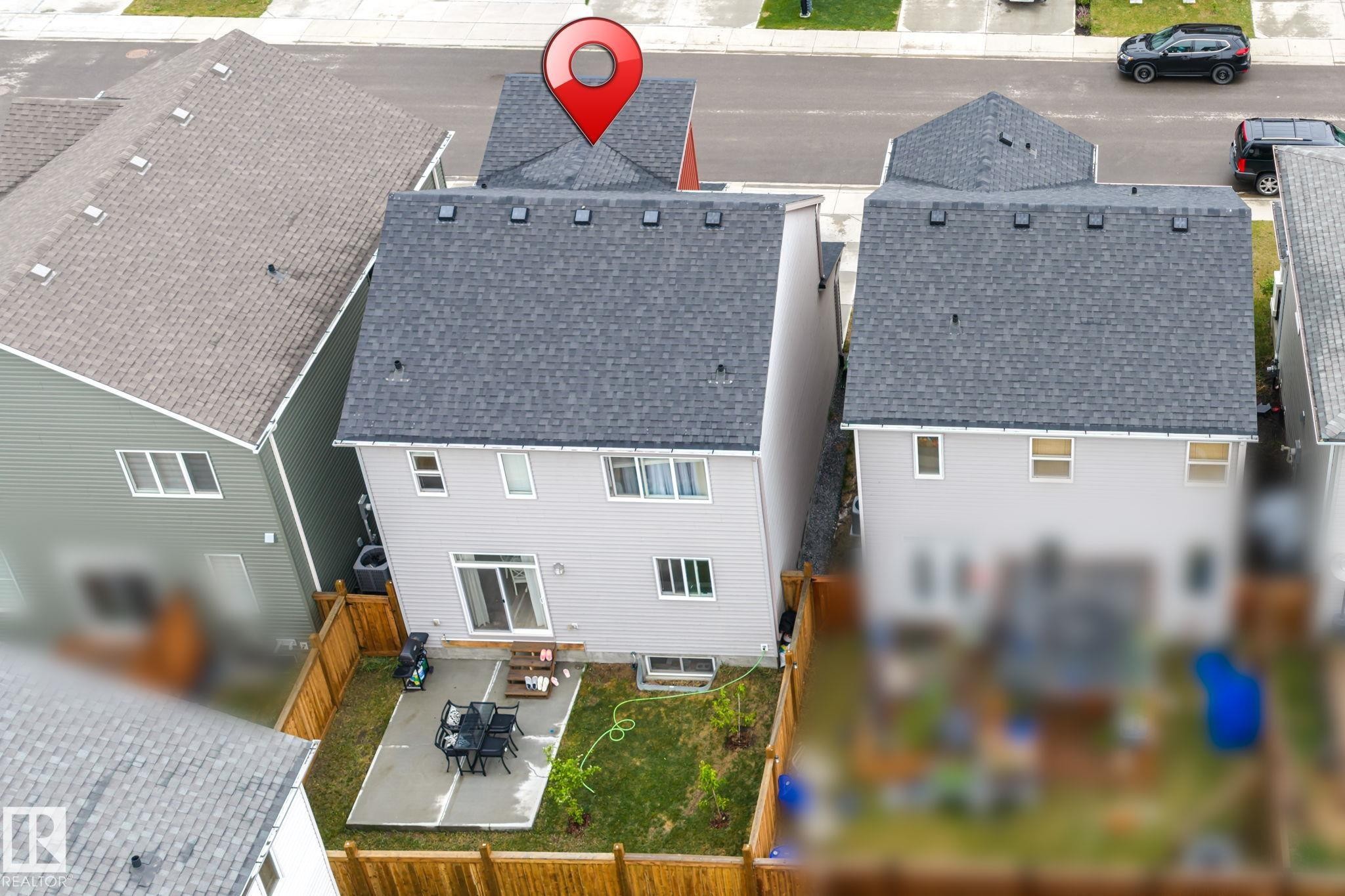 Rear exterior featuring light grey siding, a sliding glass door, and a concrete patio - 20227 17Ave, Edmonton, AB