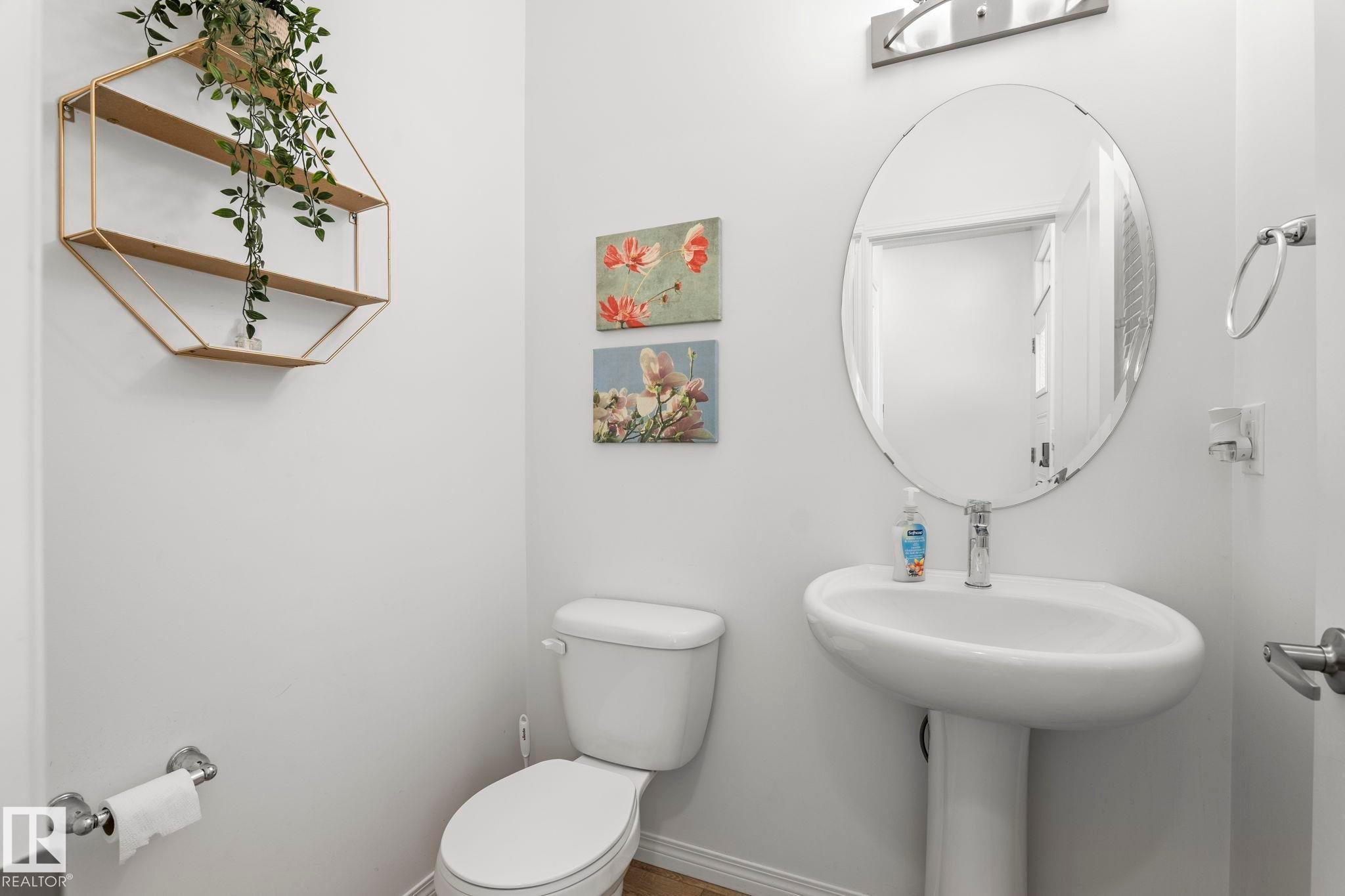 Pedestal sink with chrome faucet, an oval mirror, and chrome vanity lighting - 20227 17Ave, Edmonton, AB
