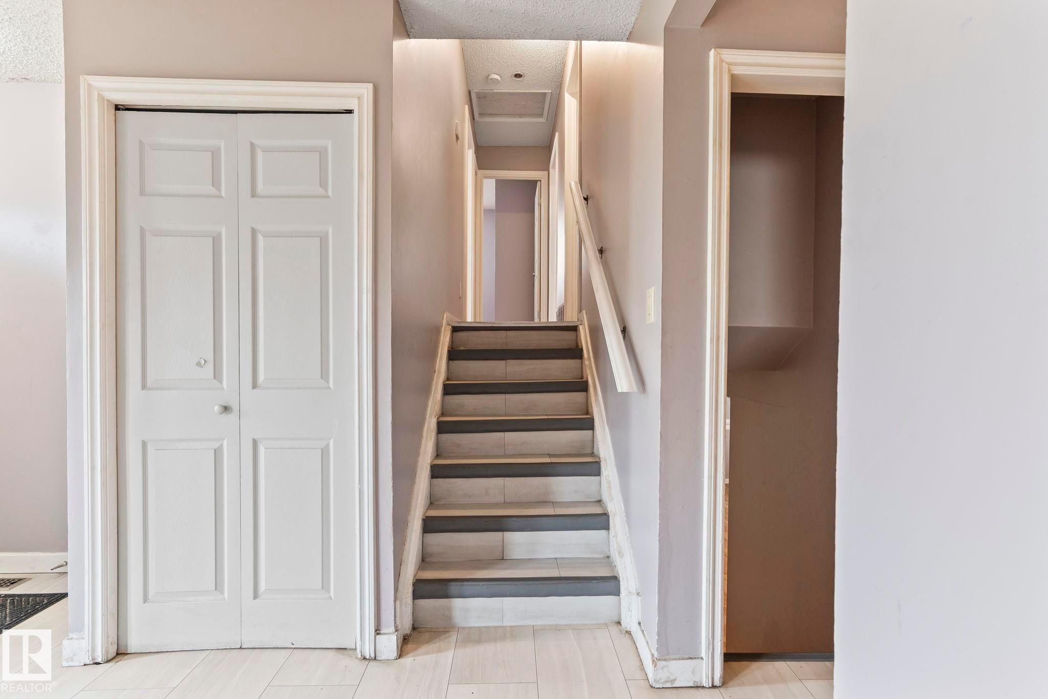 Staircase featuring wood-finish treads and risers, complemented by a white handrail - 2045 46St, Edmonton, AB