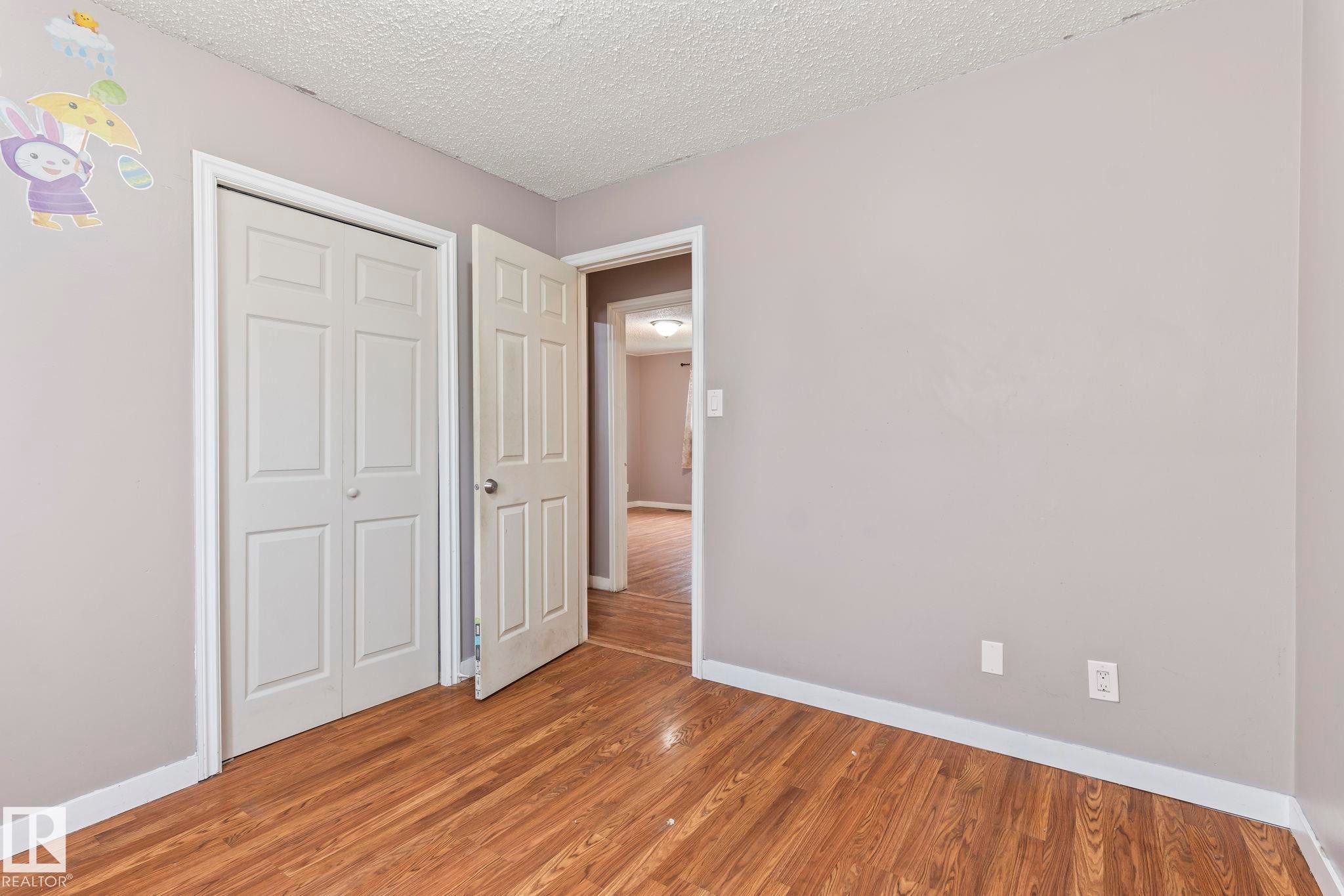 Neutral gray wall paint with white trim, wood-finish flooring, and white paneled doors - 2045 46St, Edmonton, AB