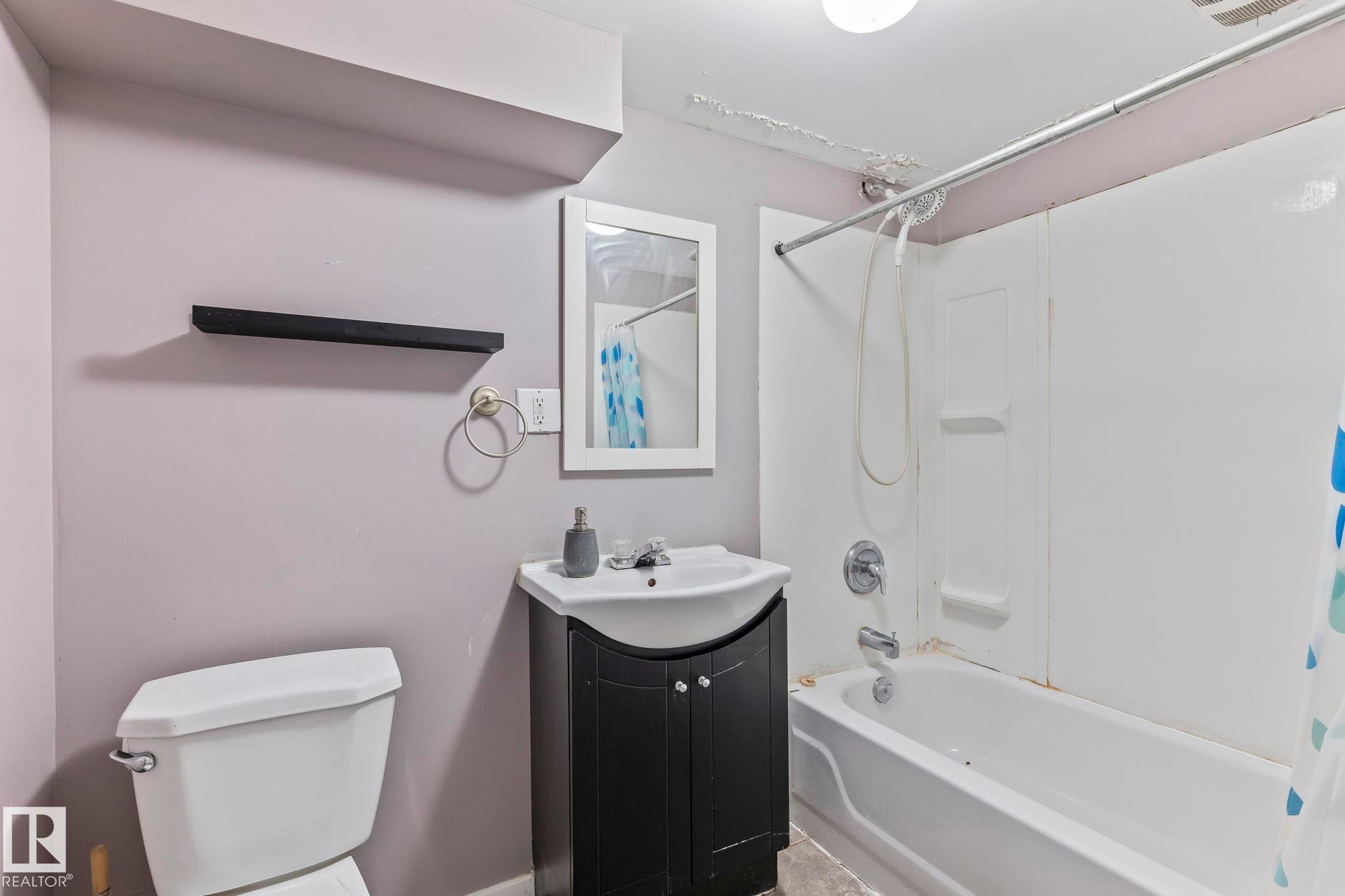 Bathroom featuring a white bathtub, wall-mounted shower, and a dark wood-finish vanity with an integrated sink - 2045 46St, Edmonton, AB