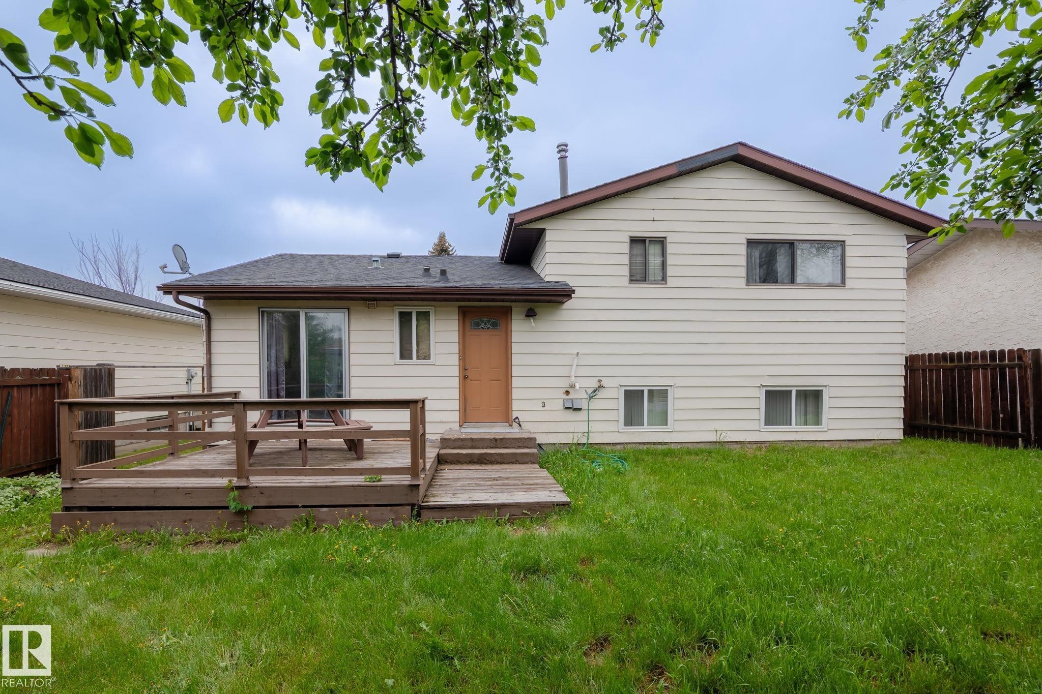 Rear exterior featuring light-colored horizontal siding and a brown shingle roof - 2045 46St, Edmonton, AB
