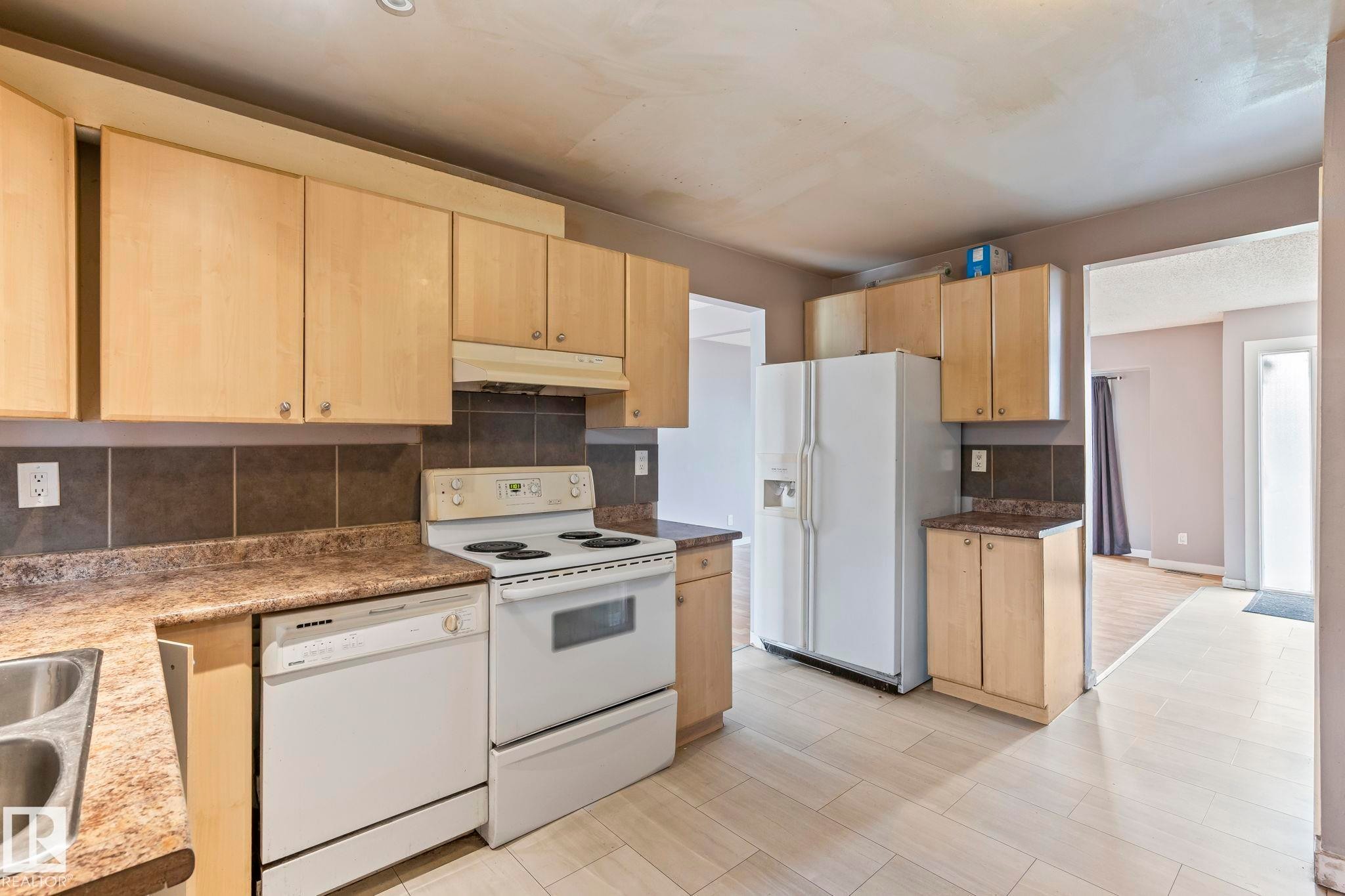Kitchen featuring light wood-finish cabinetry, a white electric range, and a white dishwasher - 2045 46St, Edmonton, AB