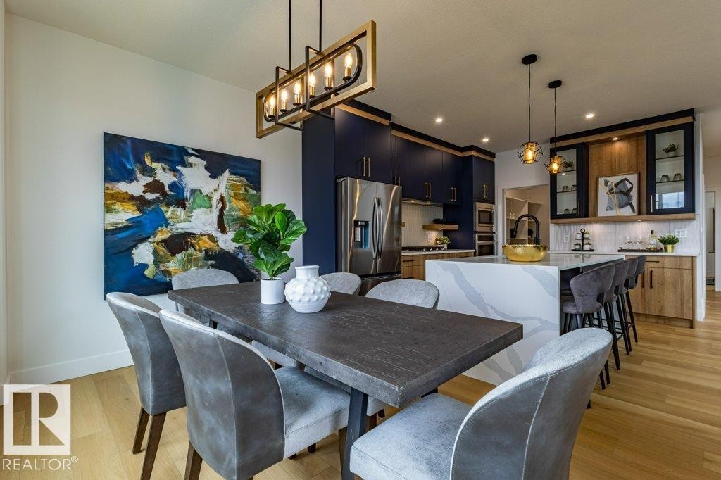 Open-concept dining area featuring a linear chandelier with a gold and black finish - 82 Wynn Rd, Fort Saskatchewan, AB