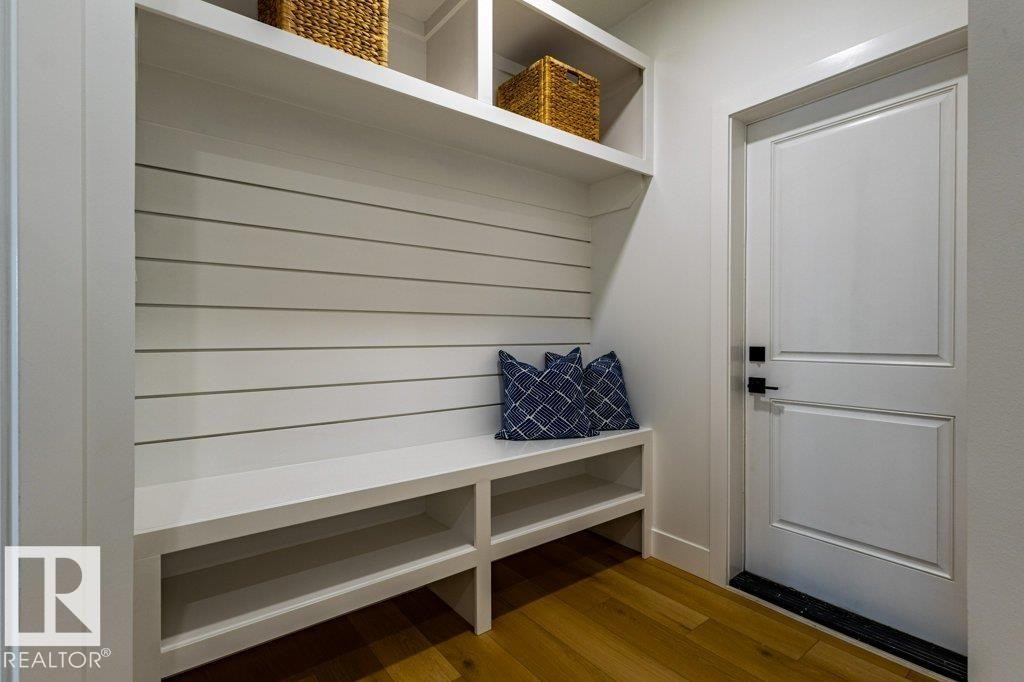 Built-in bench seating with storage cubbies and upper shelving, complemented by a white shiplap back panel and durable wood-finish flooring - 82 Wynn Rd, Fort Saskatchewan, AB
