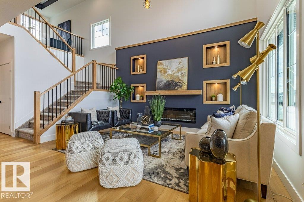 Two-story living area featuring light wood-finish flooring, a contemporary fireplace with a wood mantle, and built-in wall niches - 82 Wynn Rd, Fort Saskatchewan, AB