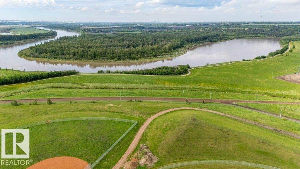 Expansive green spaces featuring a baseball diamond, winding walking paths, mature forested areas, and a prominent river - 82 Wynn Rd, Fort Saskatchewan, AB