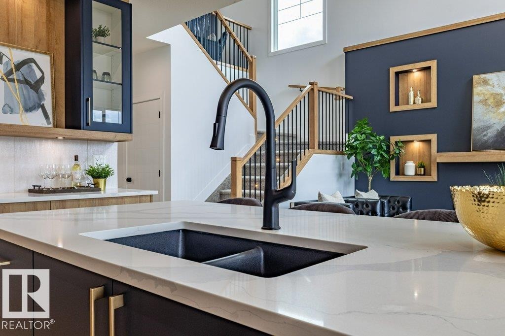Kitchen island featuring a black composite sink with a matte black pull-down faucet, paired with white stone-finish countertops - 82 Wynn Rd, Fort Saskatchewan, AB
