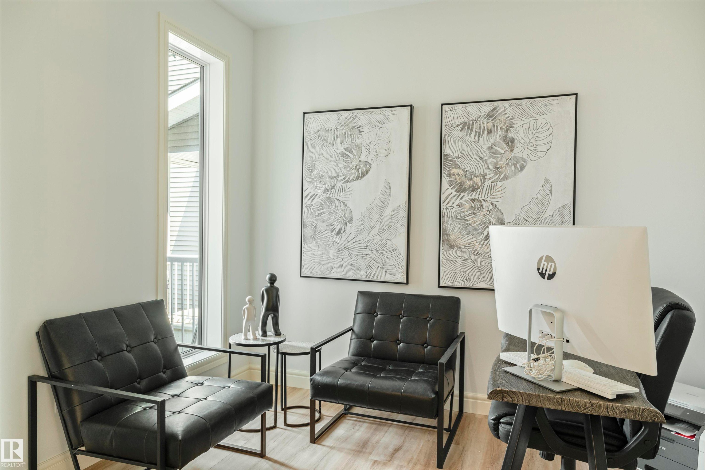 Bright interior space featuring a tall, slender window, wood-finish flooring, and light-toned walls - 3329 Chickadee Drive, Edmonton, AB