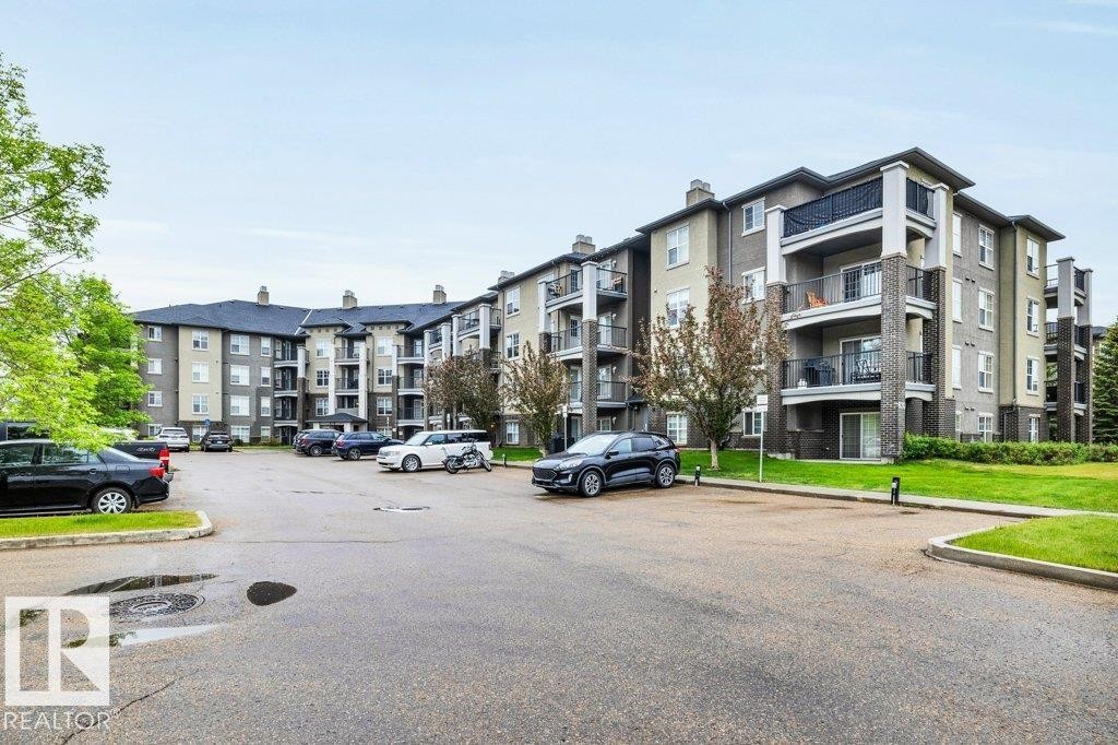 Multi-story residential building featuring a combination of light-colored and dark-toned exterior siding with brick accents - 116 630 Mcallister Loop, Edmonton, AB