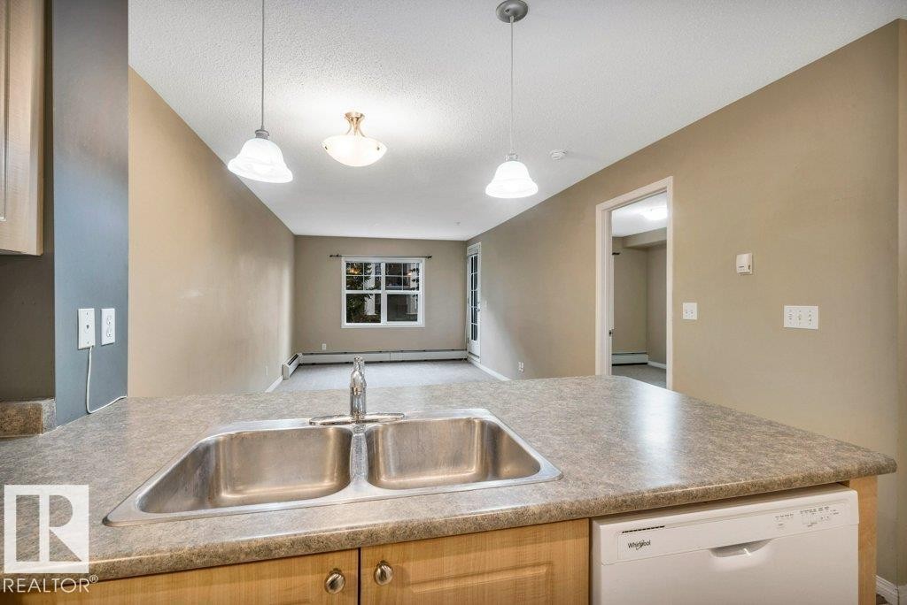 Kitchen counter with a double stainless steel sink and a chrome faucet - 116 630 Mcallister Loop, Edmonton, AB