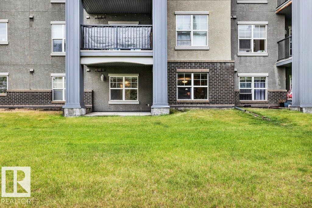 Expansive green lawn fronting a multi-story building featuring stucco and brick finishes - 116 630 Mcallister Loop, Edmonton, AB