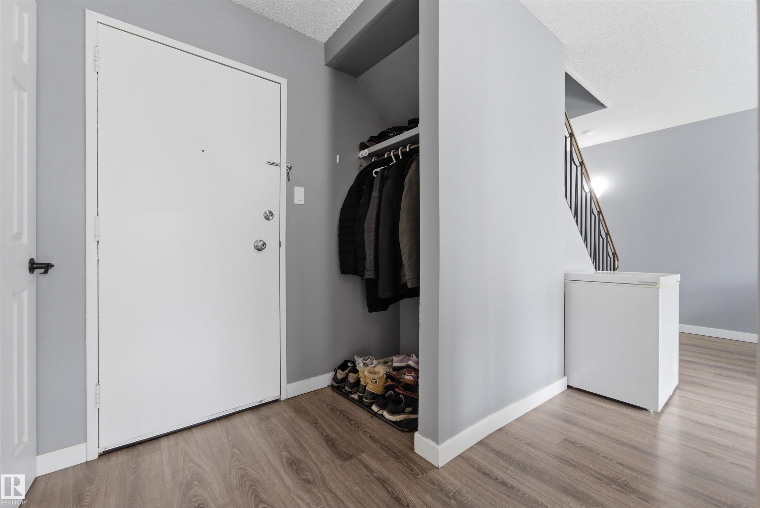 Entryway featuring wood-finish flooring, light gray wall paint, and white trim - #110 7805 159 St Nw, Edmonton, AB
