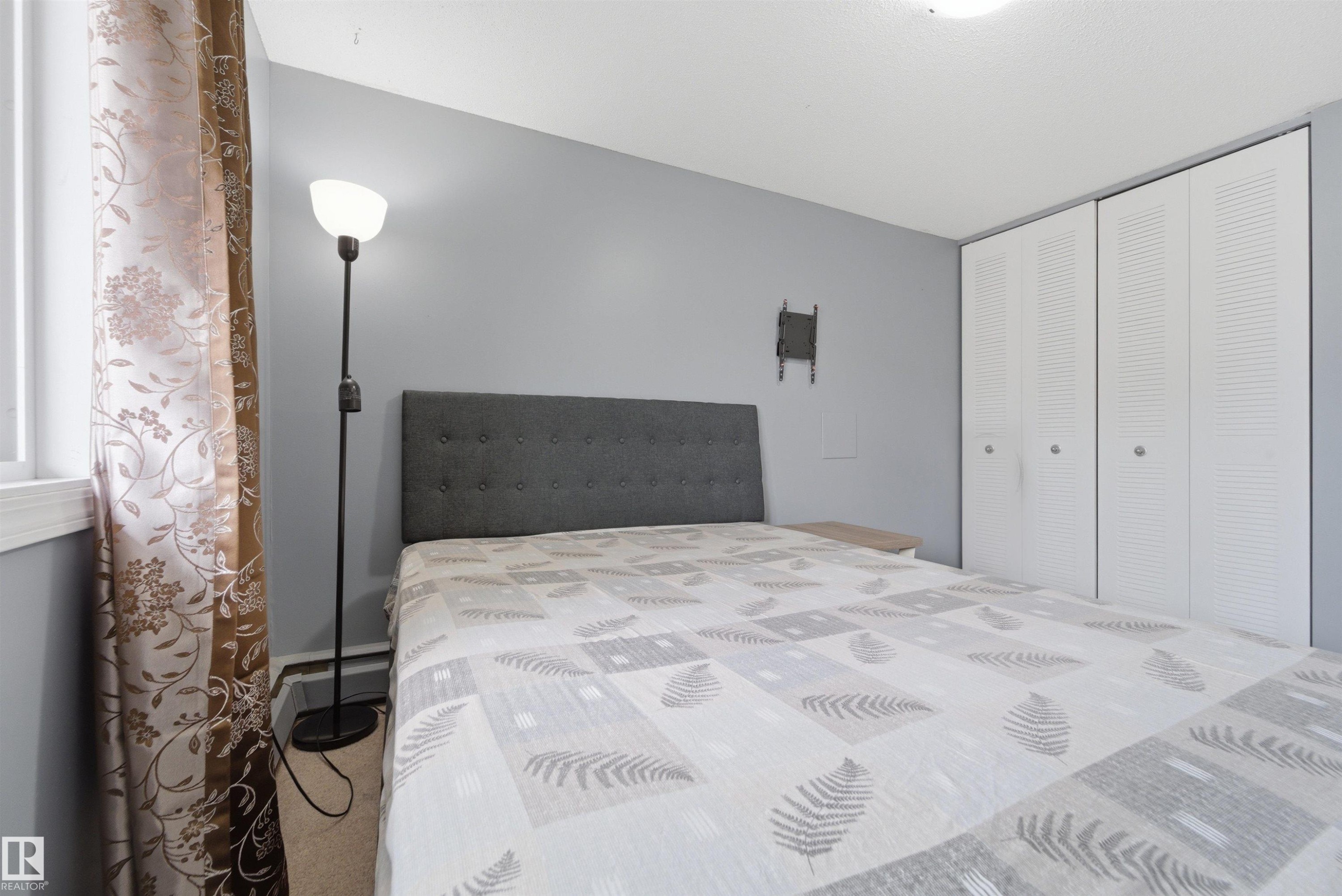 Bedroom featuring light grey walls, carpet flooring, and a window with white trim - #110 7805 159 St Nw, Edmonton, AB