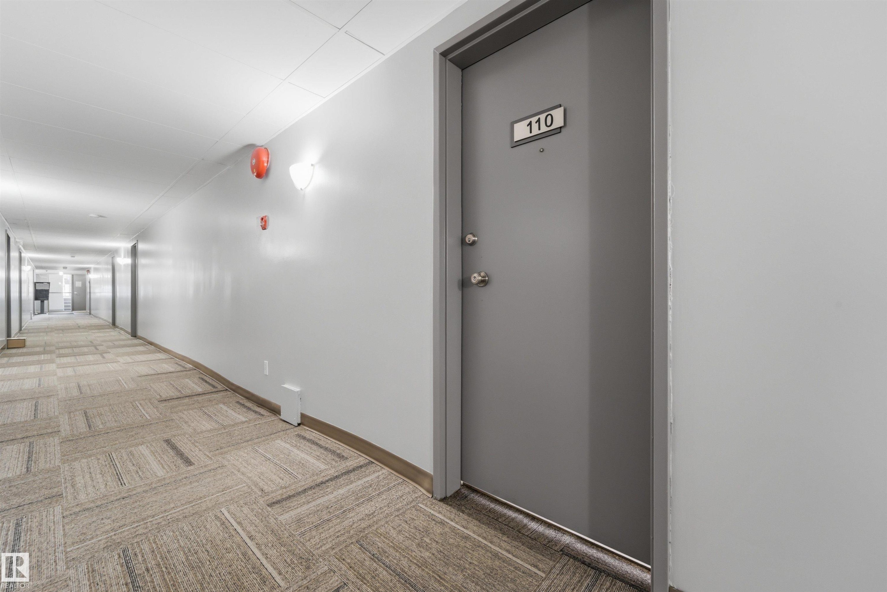 Entry door with number 110, featuring a matte gray finish and polished chrome hardware - #110 7805 159 St Nw, Edmonton, AB