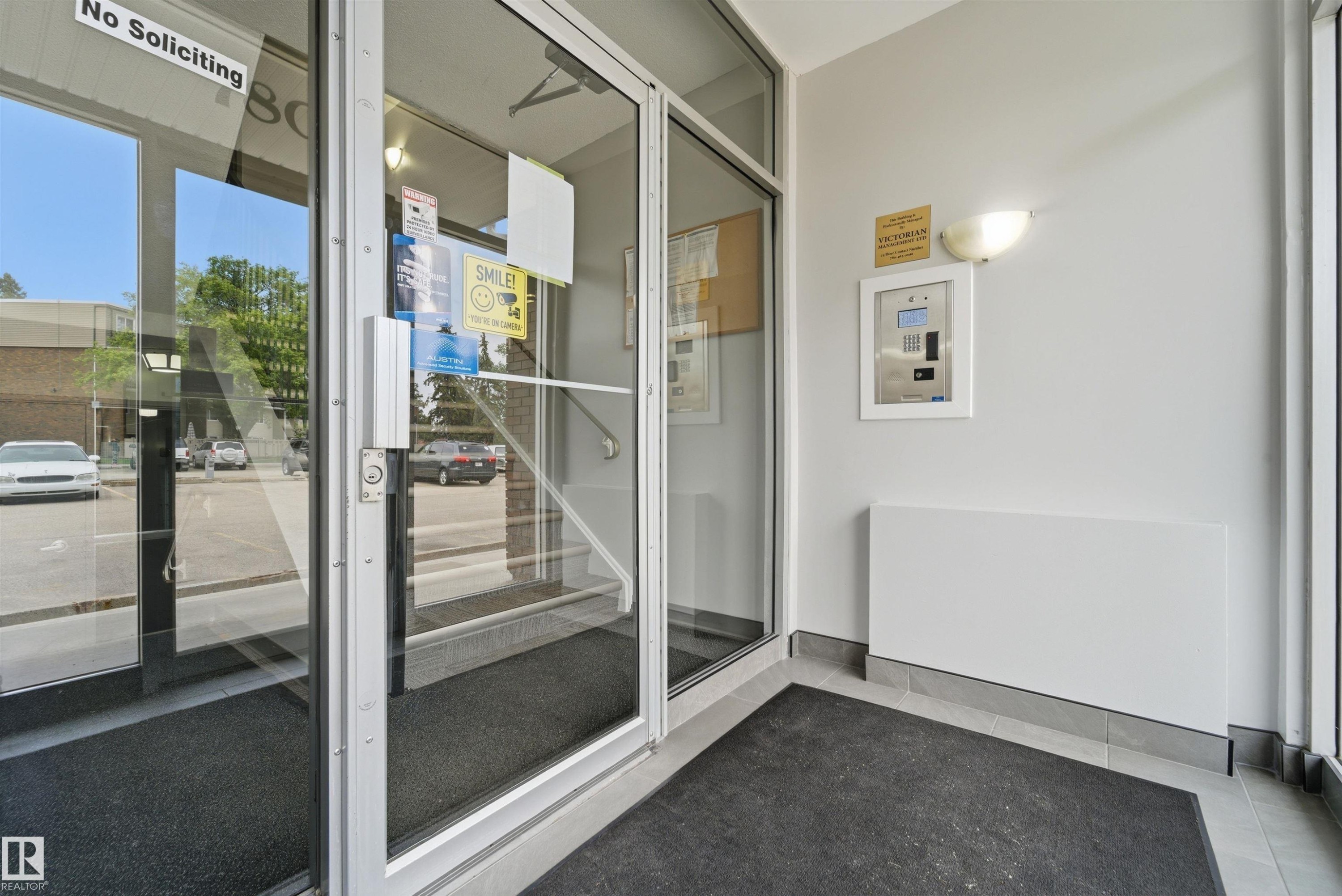Building entrance featuring a glass door, aluminum frame, and an intercom system - #110 7805 159 St Nw, Edmonton, AB