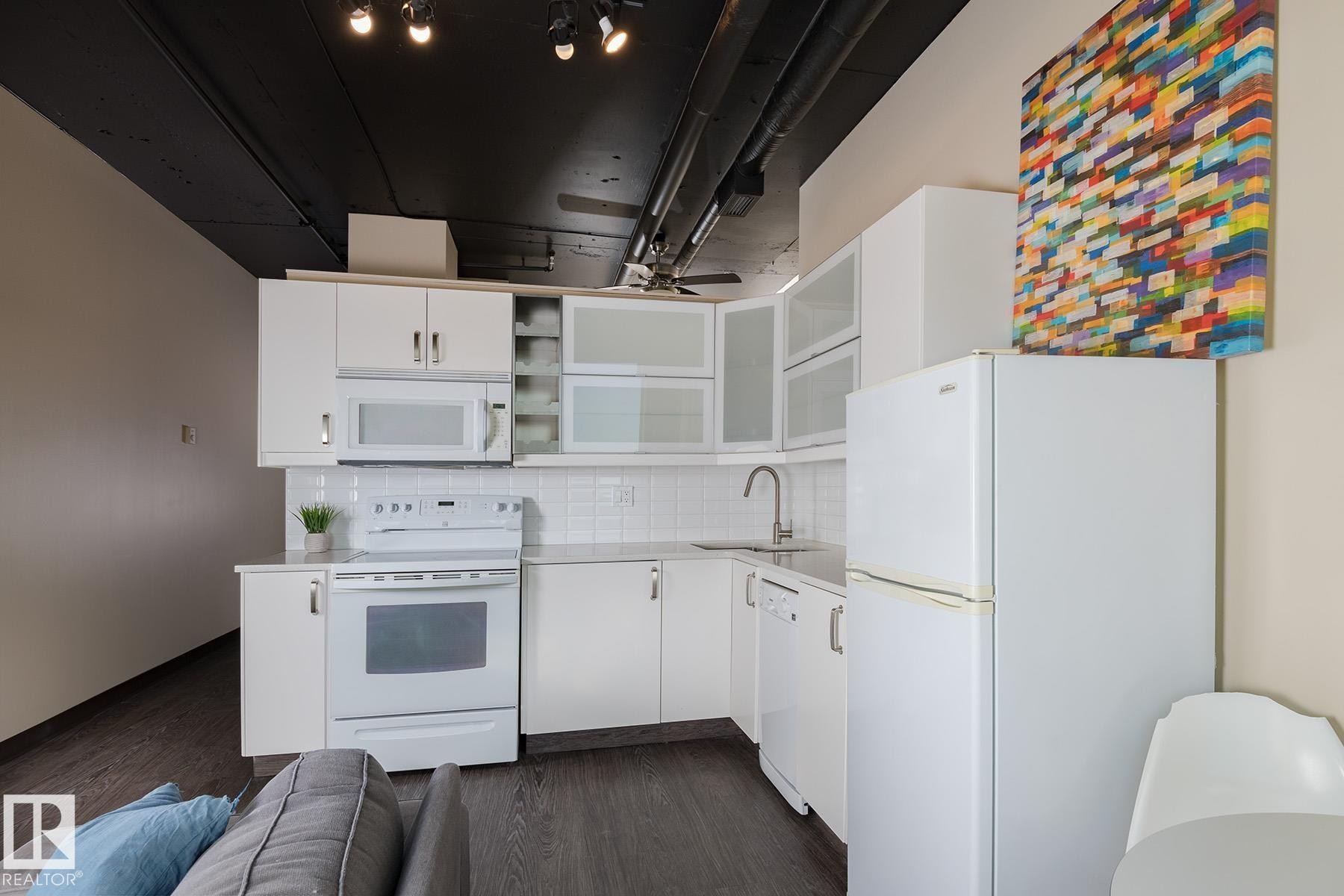 Compact kitchen featuring white cabinetry, white subway tile backsplash, and white appliances - 411 10024 Jasper Avenue, Edmonton, AB
