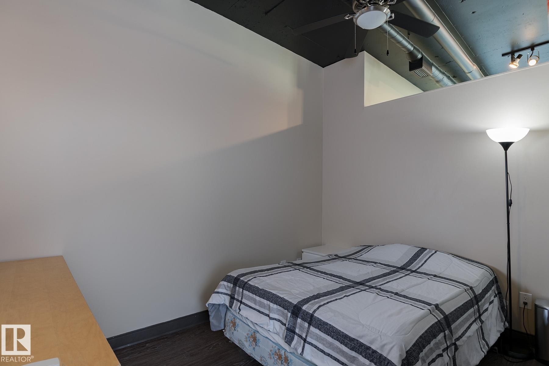Room featuring a ceiling fan, exposed ductwork, track lighting, and dark wood-finish flooring - 411 10024 Jasper Avenue, Edmonton, AB