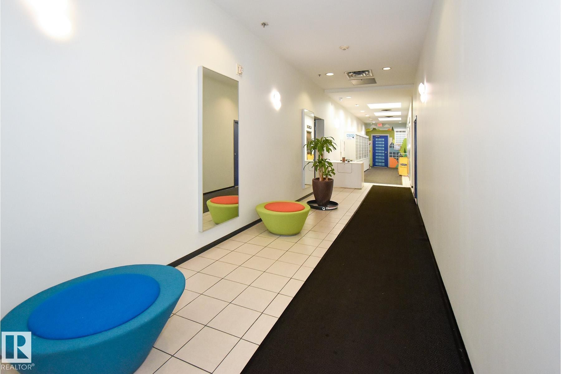 Hallway featuring white walls and a combination of square tile flooring and dark carpet runner - #412 10024 Jasper Av Nw, Edmonton, AB - Indoor Photo Showing Other Room
