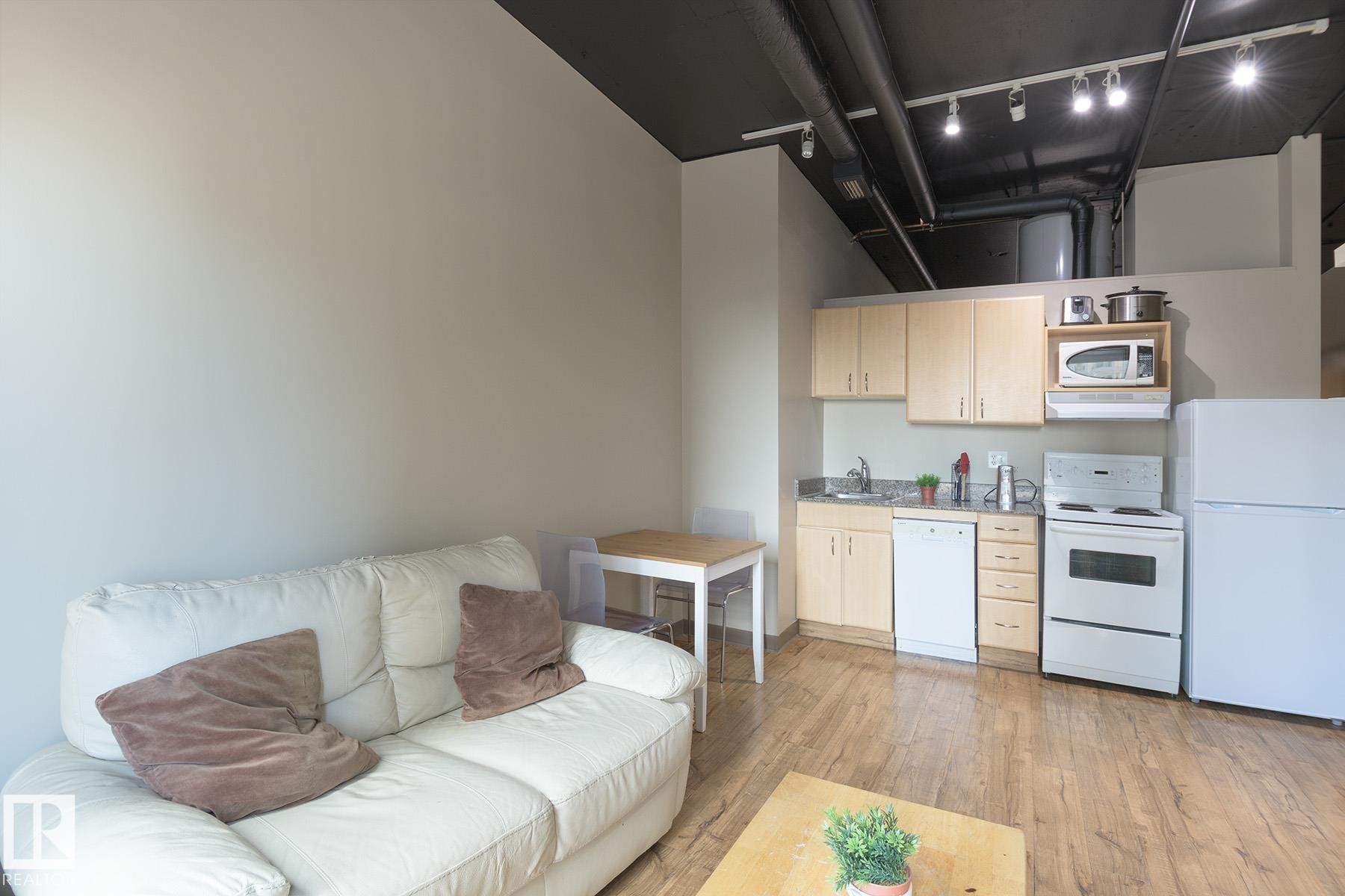 Compact kitchen featuring light wood-finish cabinetry, granite-style countertops, and white appliances - #412 10024 Jasper Av Nw, Edmonton, AB - Indoor
