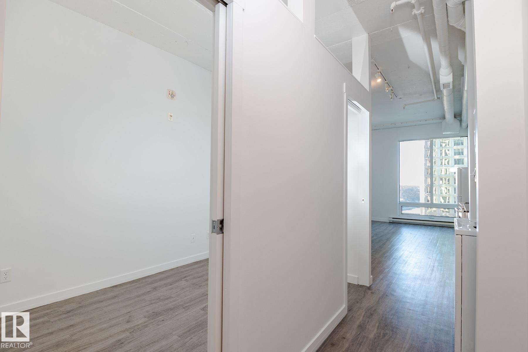 Interior space with light wood-finish flooring and a white color palette throughout - 910 10024 Jasper Avenue, Edmonton, AB