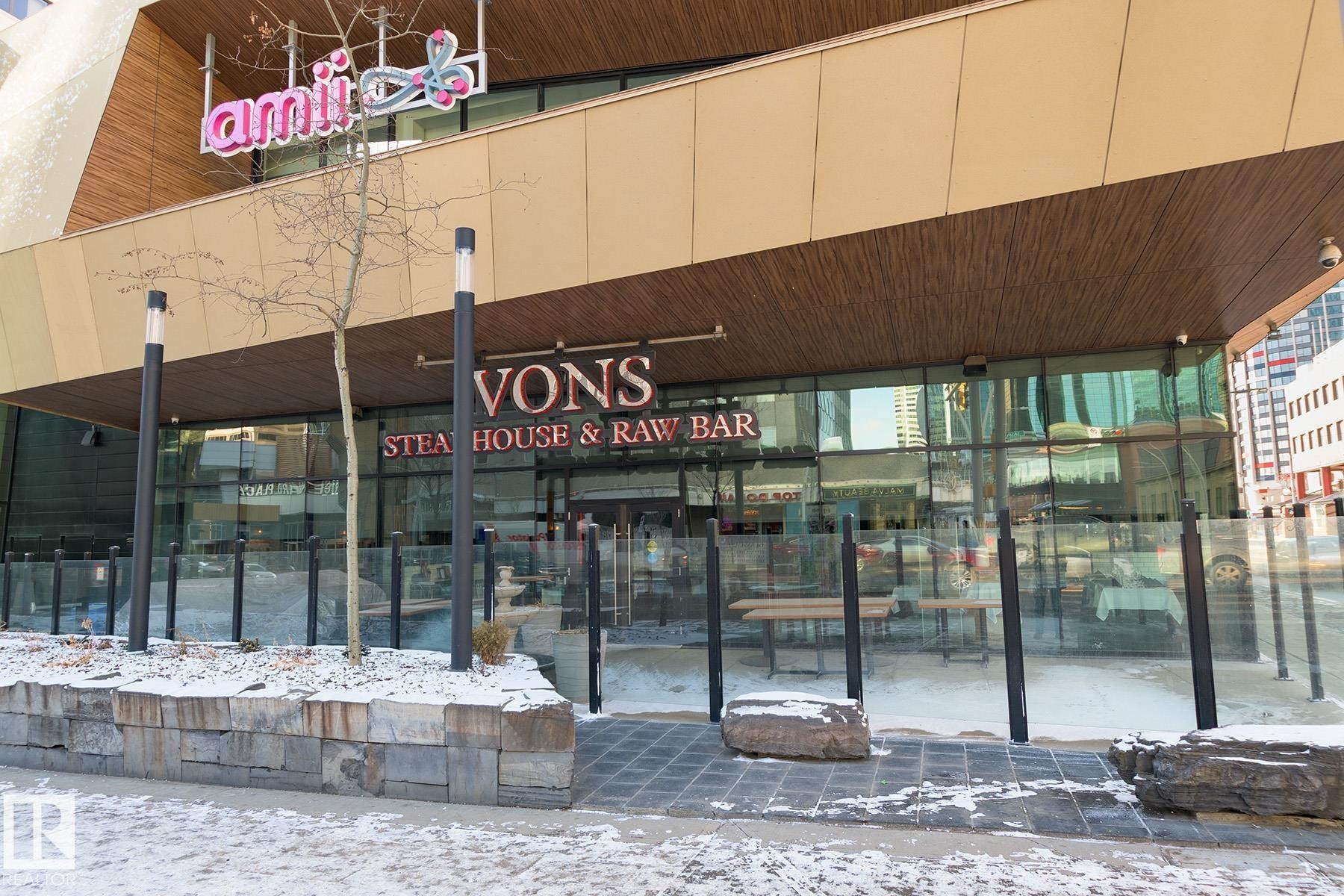 Commercial storefront featuring full-height glass frontage, an expansive wood-finish ceiling overhang, and a stone-clad planter box - 910 10024 Jasper Avenue, Edmonton, AB