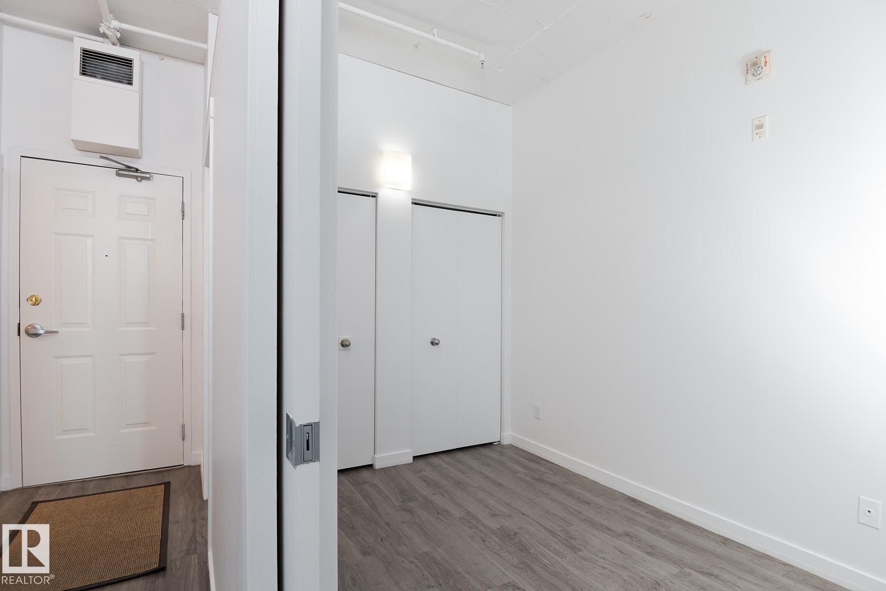 White paneled entry door with brass hardware and overhead wall heater - 910 10024 Jasper Avenue, Edmonton, AB