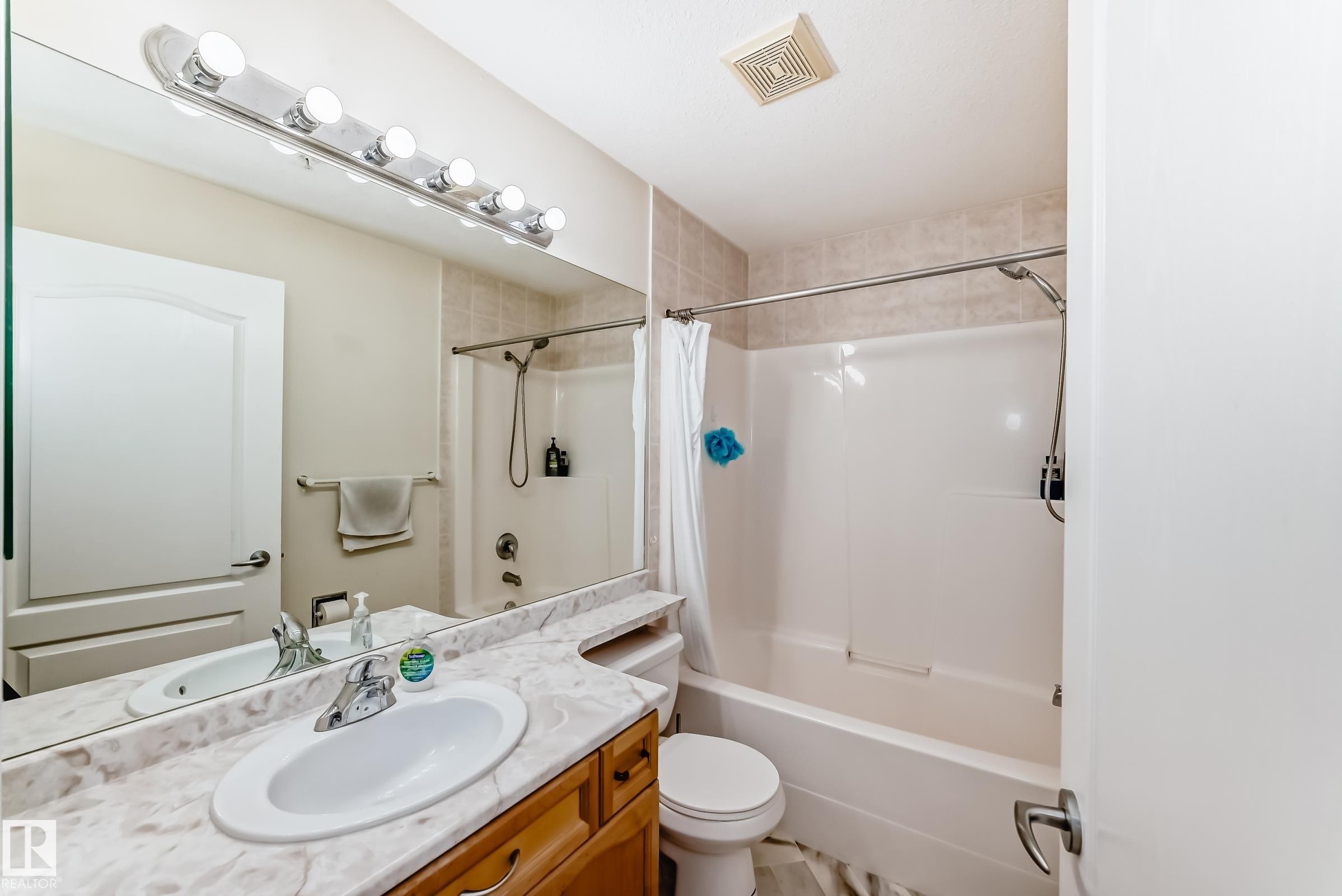 Bathroom featuring a vanity with an integrated sink, a large mirror, and a full shower-tub combination - 214 9938 104 Street, Edmonton, AB