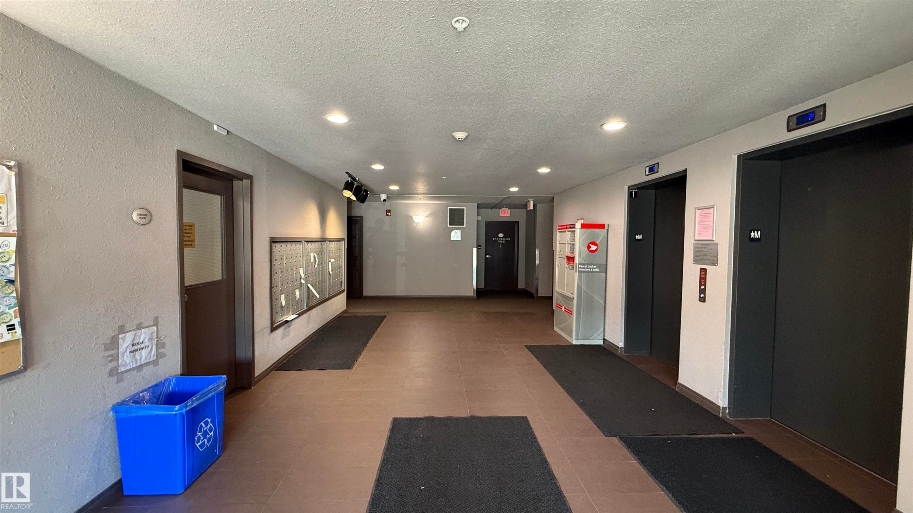 Building corridor with two elevators, recessed lighting, and individual mailboxes - 133 301 Clareview Station Drive, Edmonton, AB