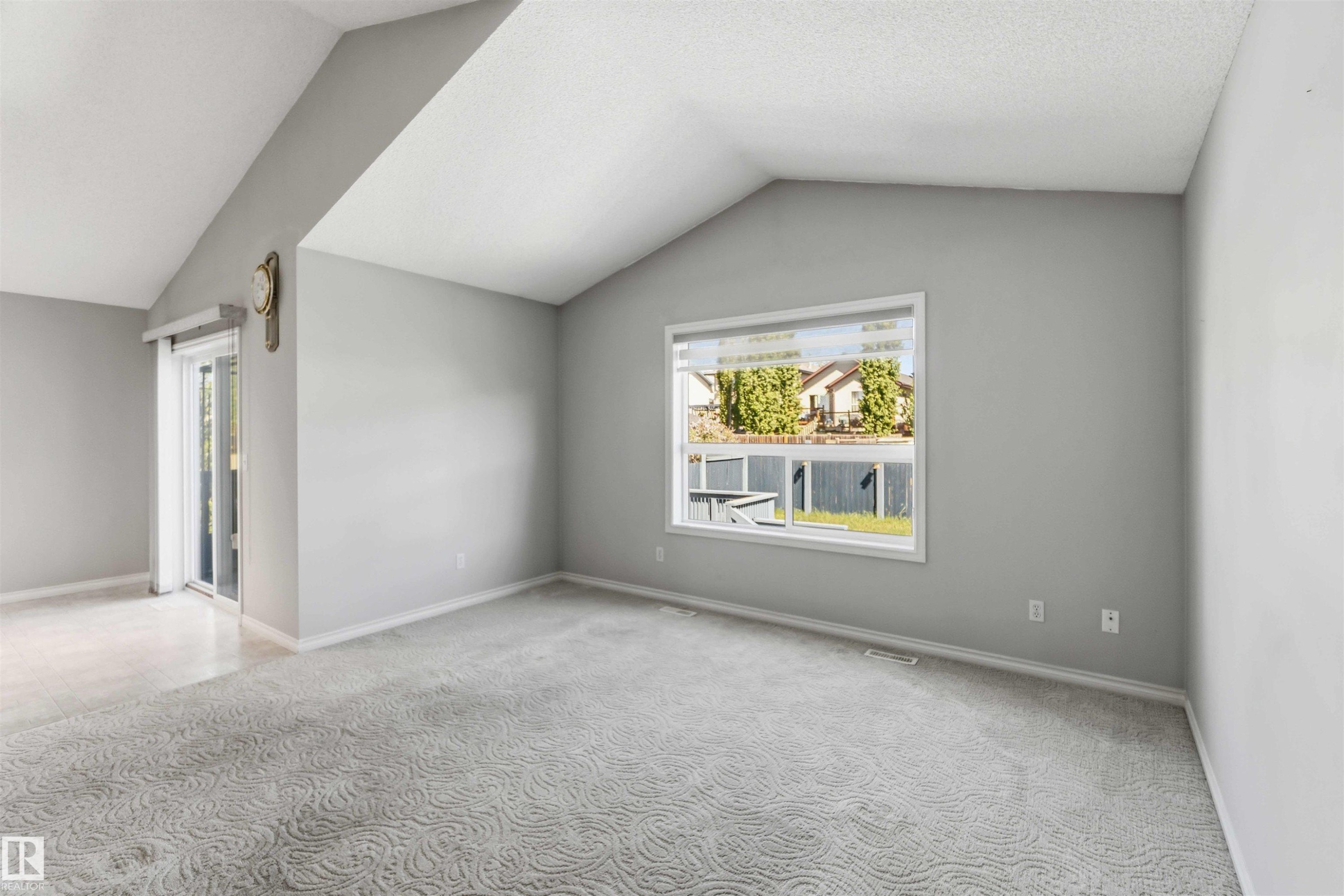 Vaulted ceiling room featuring light gray walls and patterned carpeting - 2012 35A Avenue, Edmonton, AB