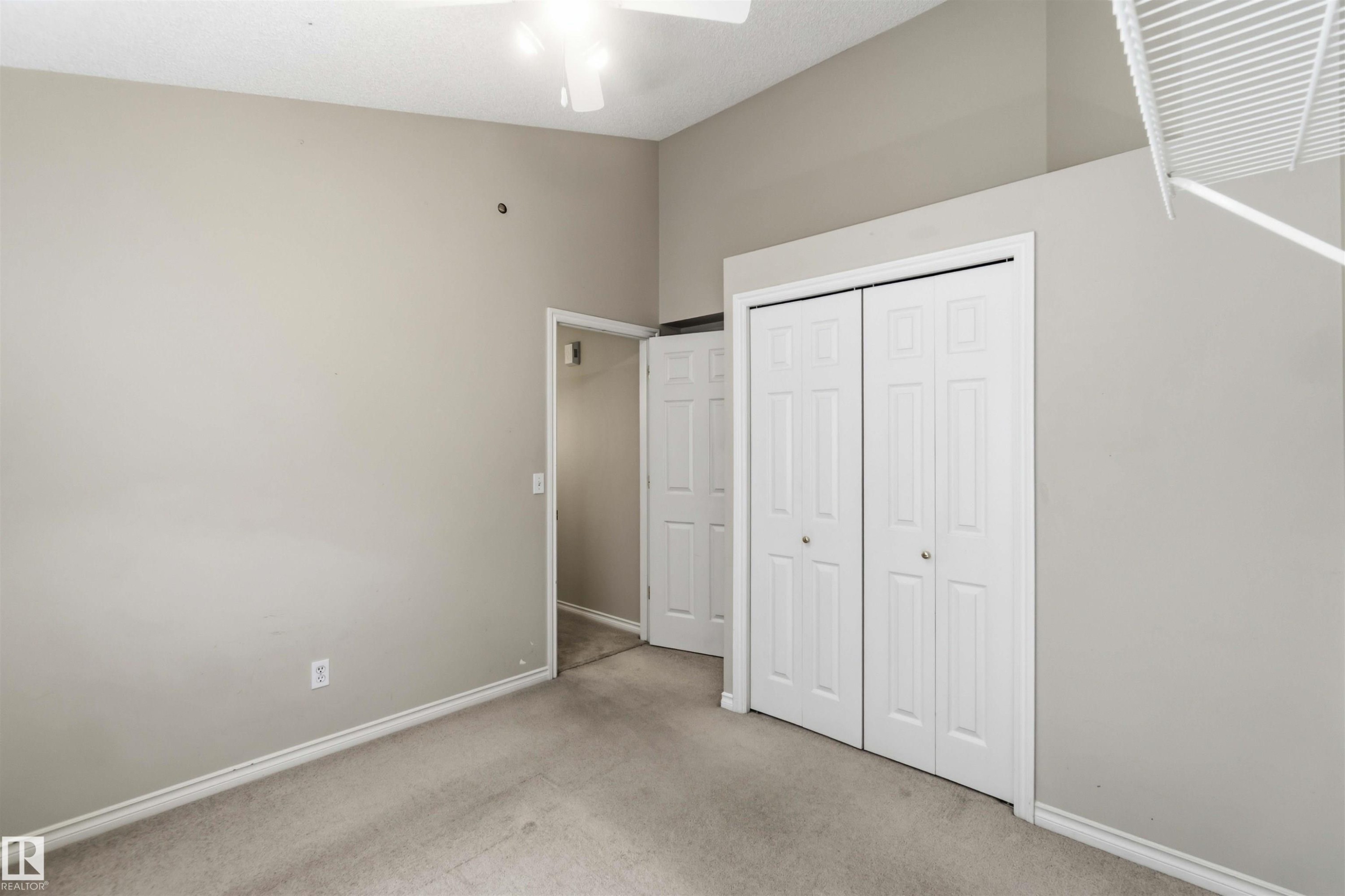 Carpeted room featuring a ceiling fan, light gray wall paint, white baseboards, and a bi-fold closet with white doors - 2012 35A Avenue, Edmonton, AB