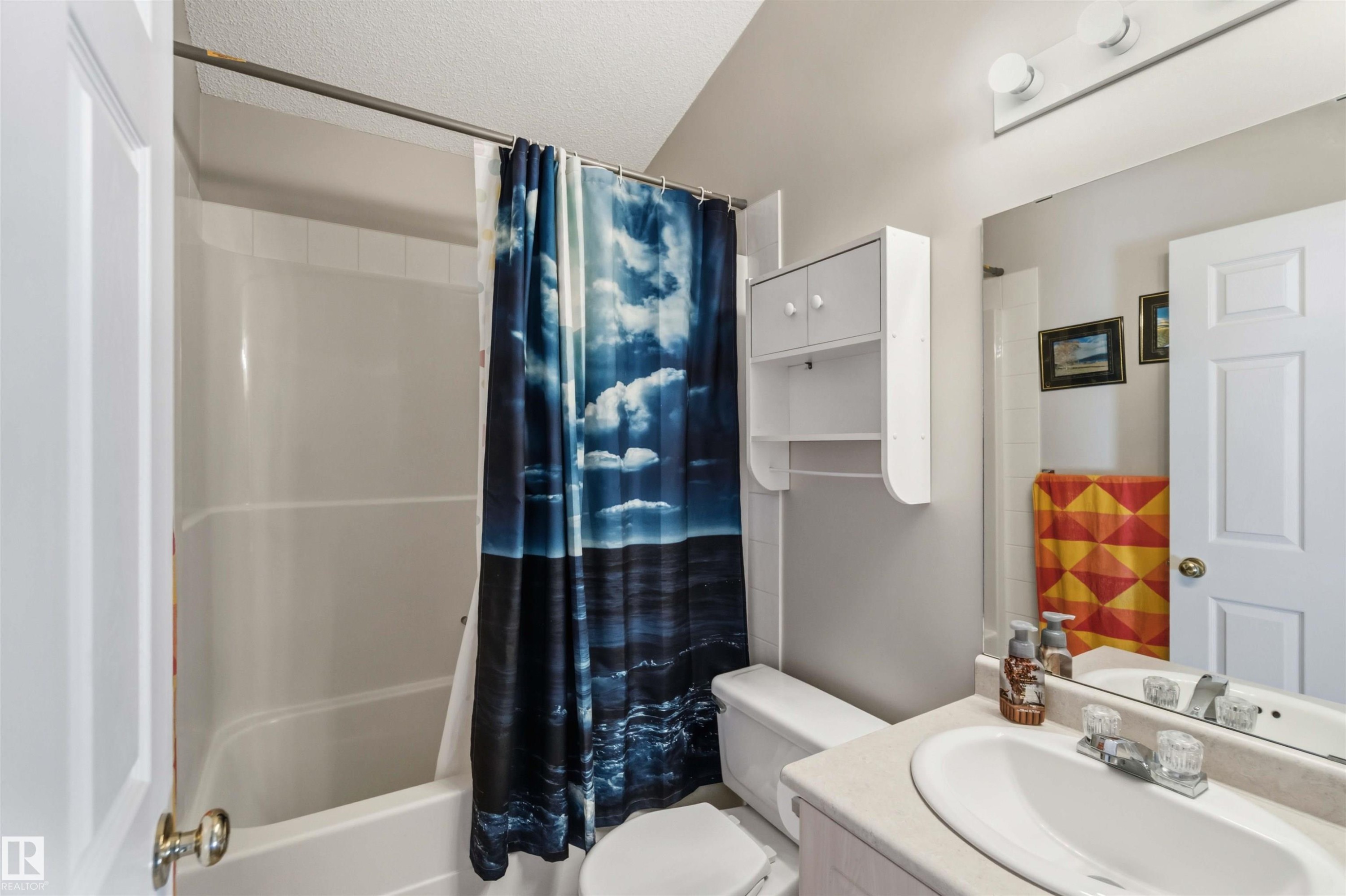 Bathroom featuring a white tub/shower combination, white toilet, and a vanity with a light-colored countertop and integrated sink - 2012 35A Avenue, Edmonton, AB