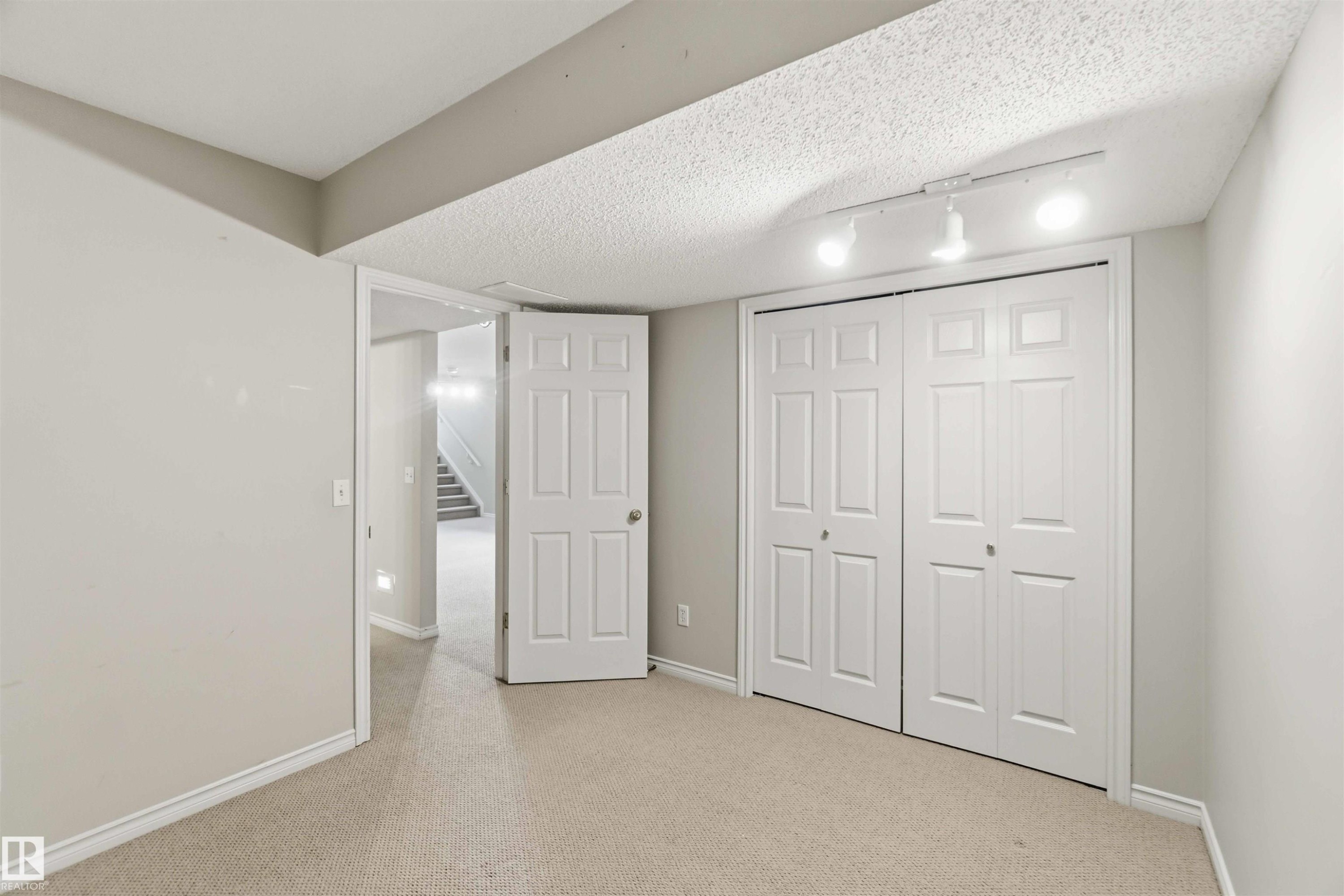 Carpeted room featuring light gray walls, white trim, and a bi-fold closet with panel doors - 2012 35A Avenue, Edmonton, AB
