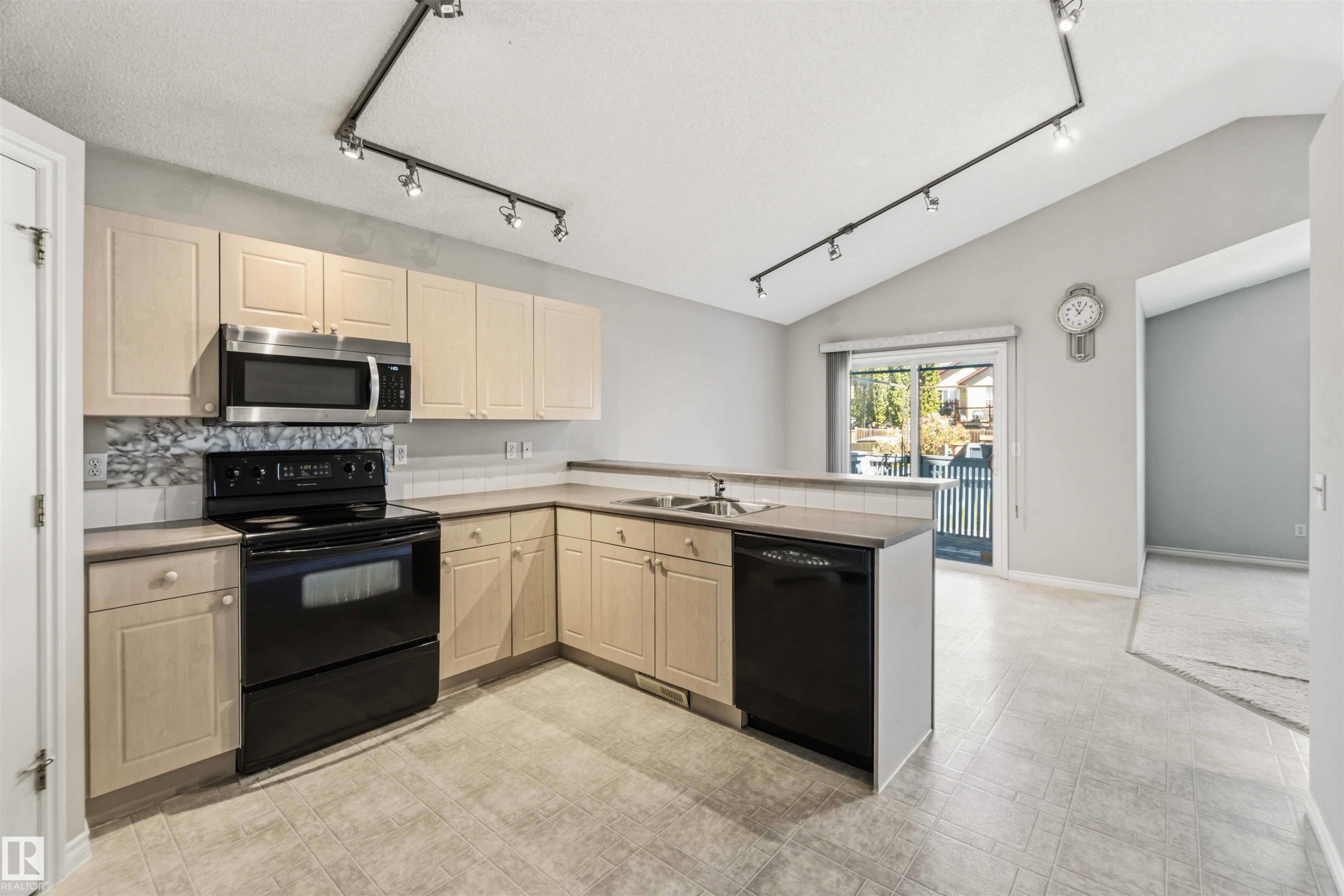 Kitchen featuring L-shaped cabinetry, track lighting, and wood-finish flooring - 2012 35A Avenue, Edmonton, AB
