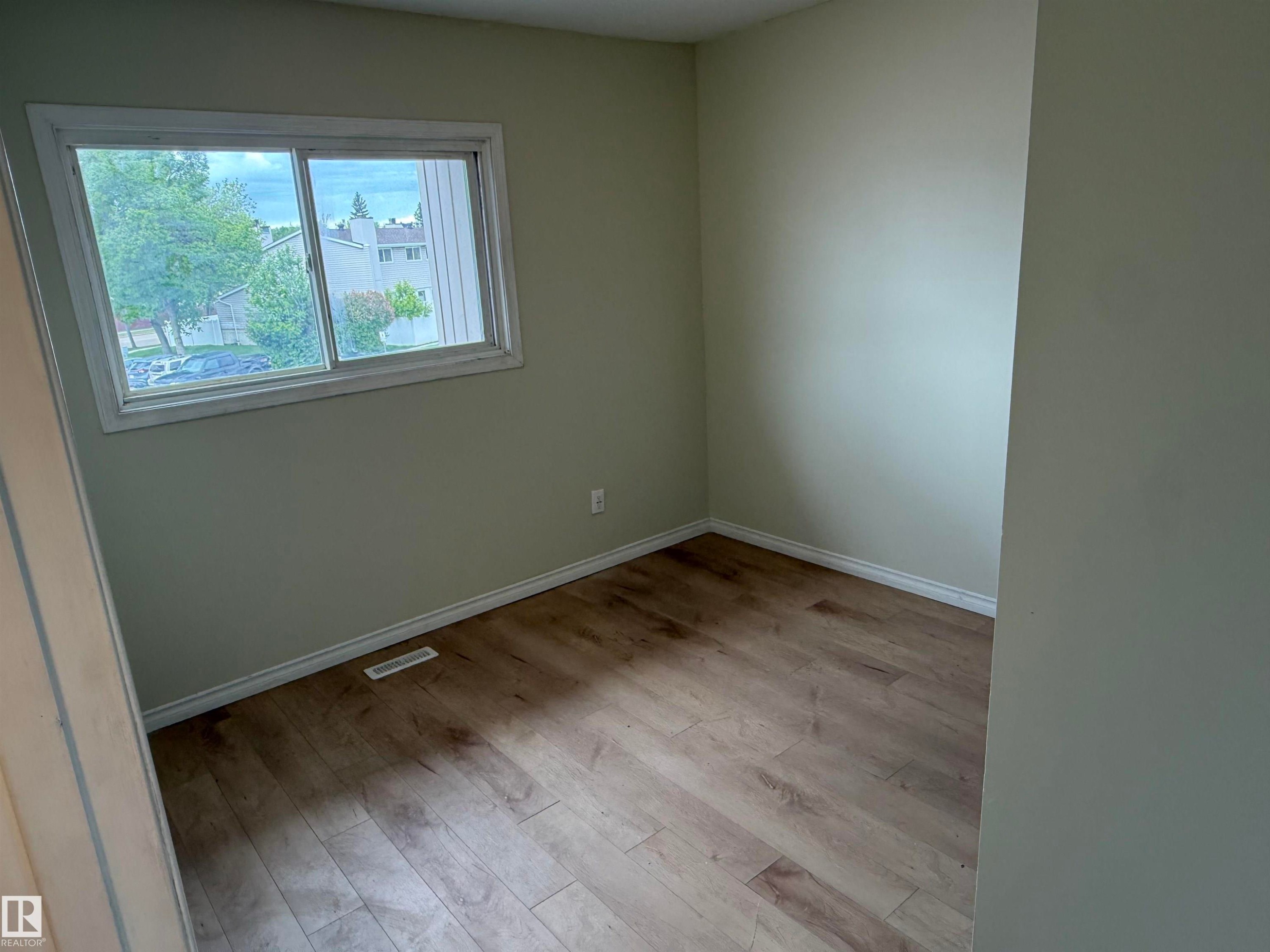 Room featuring wood-finish flooring, light-colored walls, white baseboards, and a white-trimmed window - 14537 121 Street, Edmonton, AB