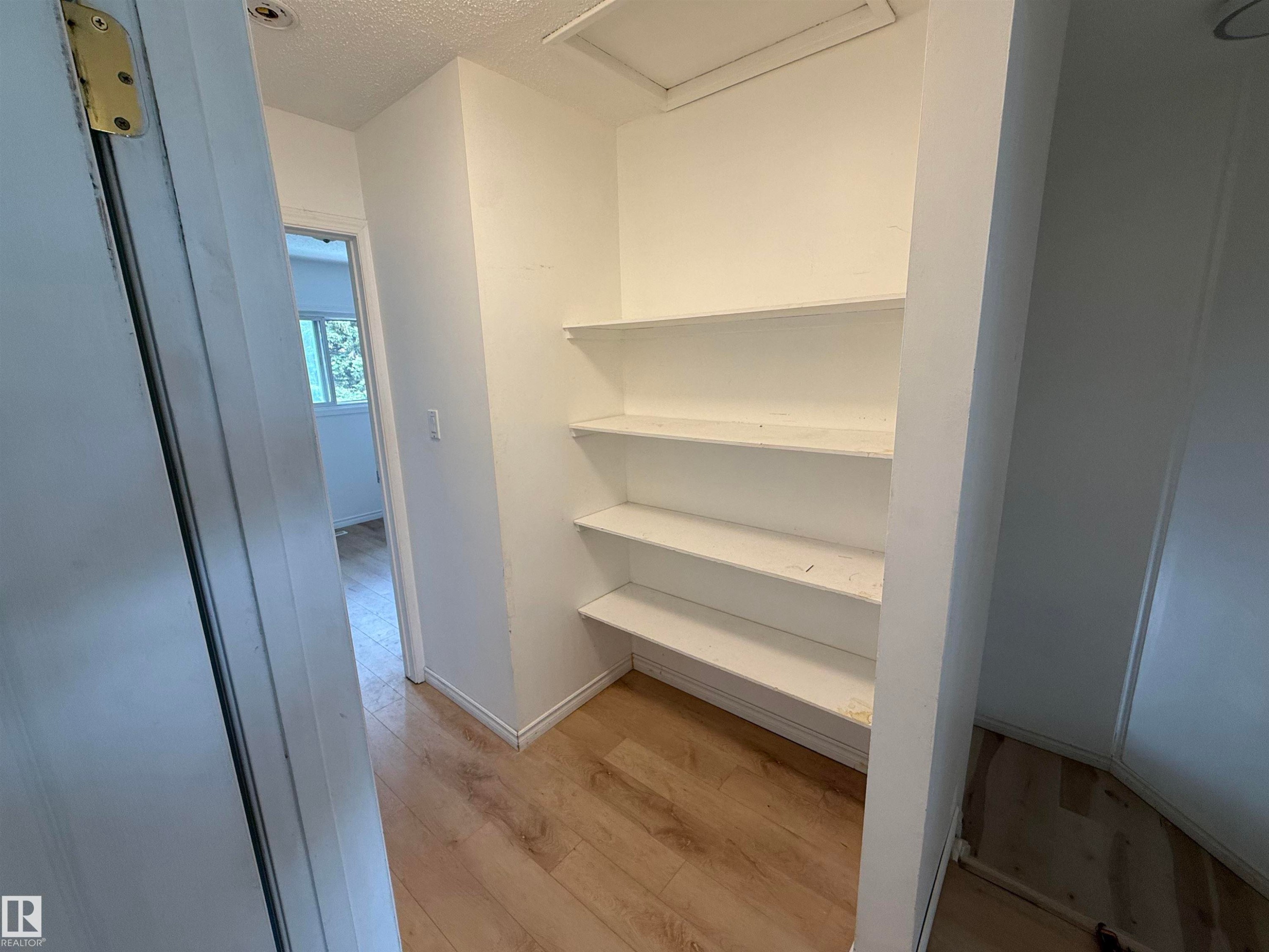 Built-in shelving unit with multiple tiers, wood-finish flooring, white baseboards, and a recessed ceiling light fixture - 14537 121 Street, Edmonton, AB