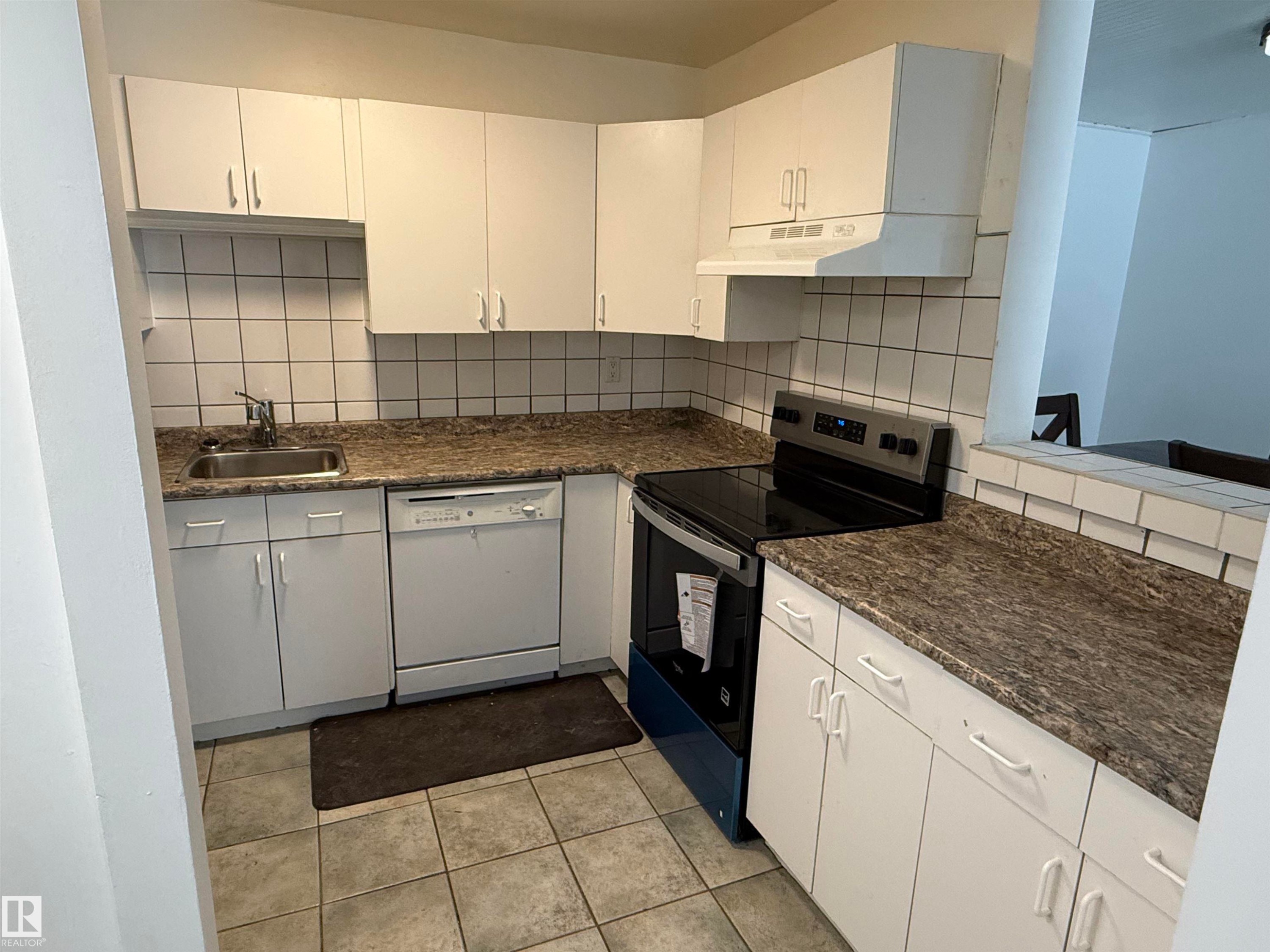 Kitchen featuring white cabinetry, tile flooring, a tile backsplash, and dark patterned countertops - 14537 121 Street, Edmonton, AB