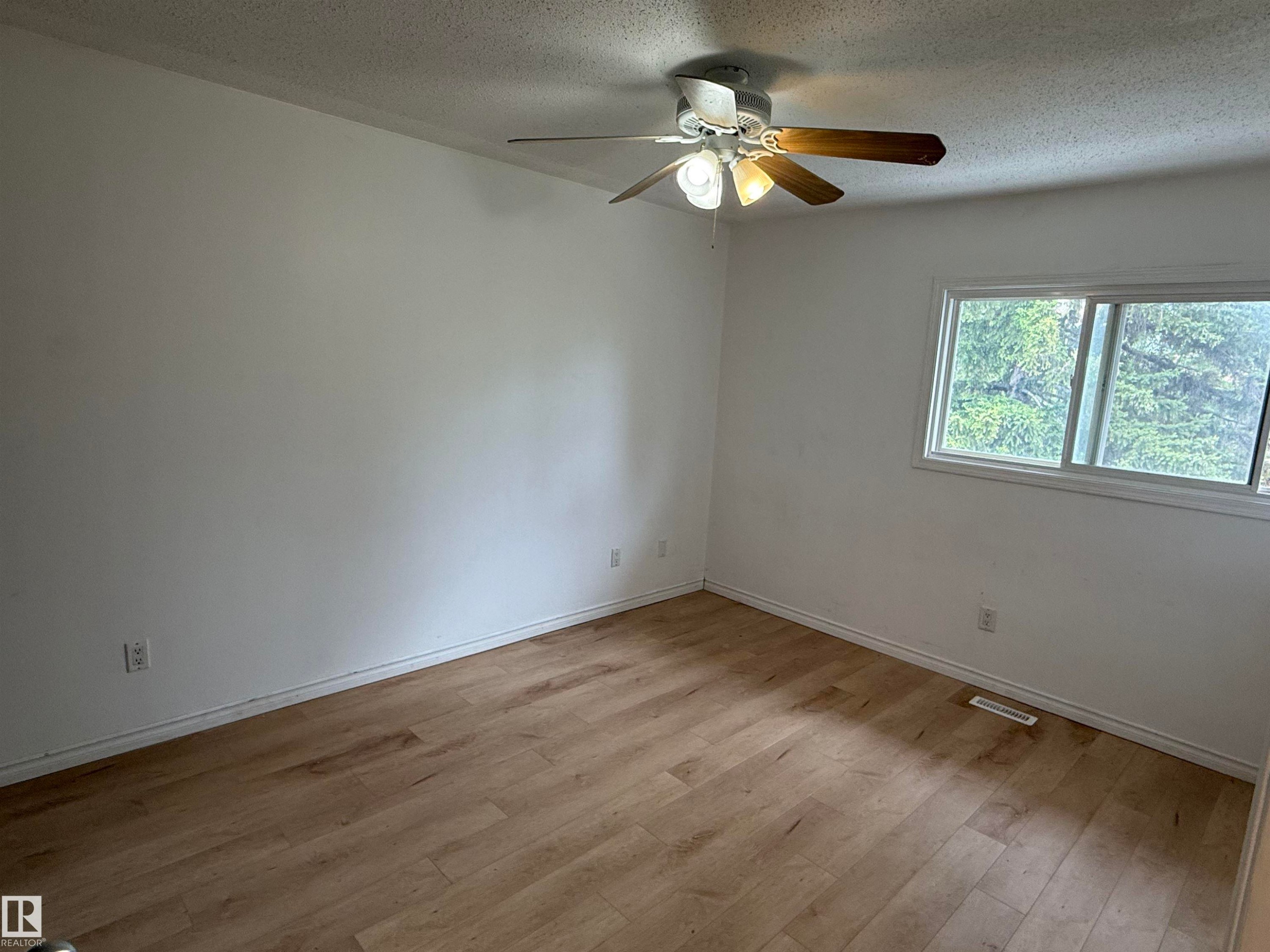 Room featuring light wood-finish flooring, white painted walls, and a ceiling fan with light fixture - 14537 121 Street, Edmonton, AB