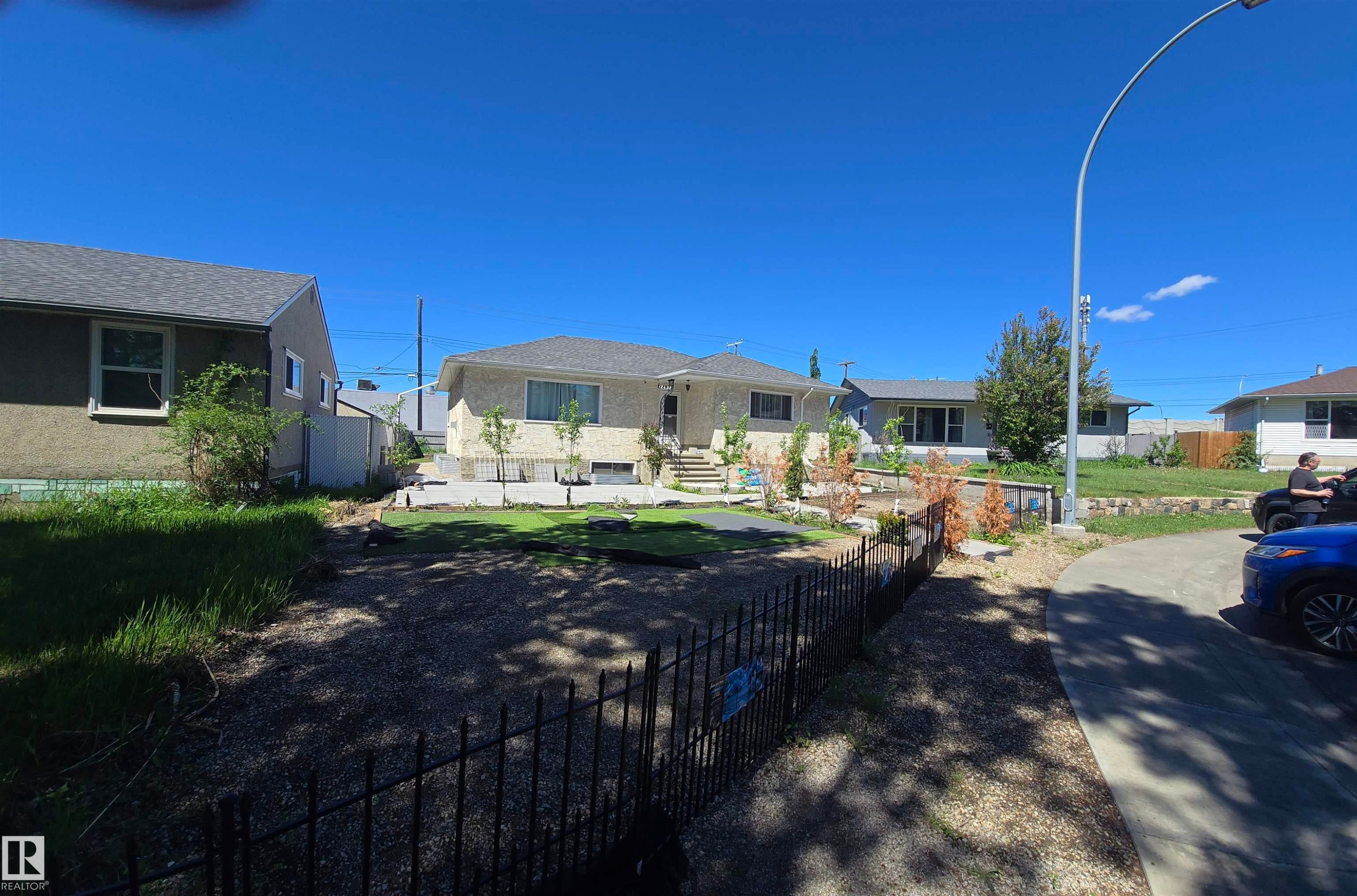 Single-family home featuring a light-colored exterior, an asphalt shingle roof, and a gravel front yard with some planted trees and shrubs - 12432 96 Street, Edmonton, AB