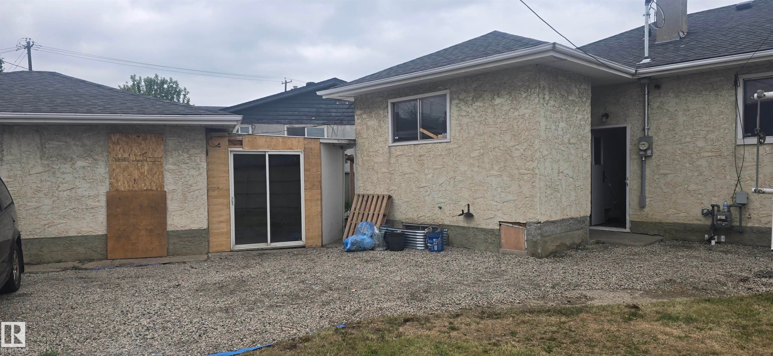 Exterior featuring light-colored stucco-finish siding, a dark shingle roof, and white window frames - 12432 96 Street, Edmonton, AB