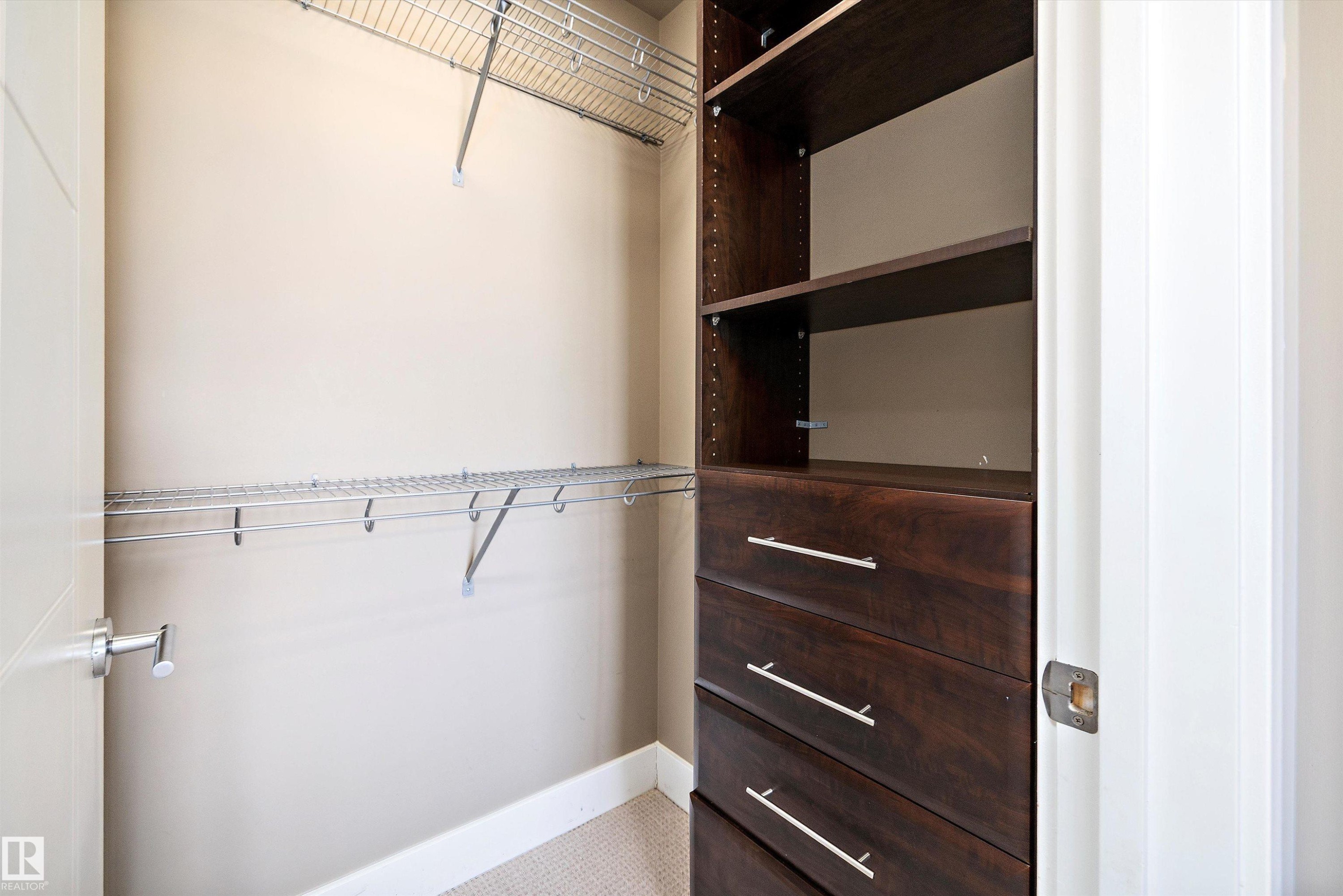 Built-in closet system featuring dark wood-finish drawers, open shelving, and chrome wire shelving - 307 11080 Ellerslie Rd Sw, Edmonton, AB